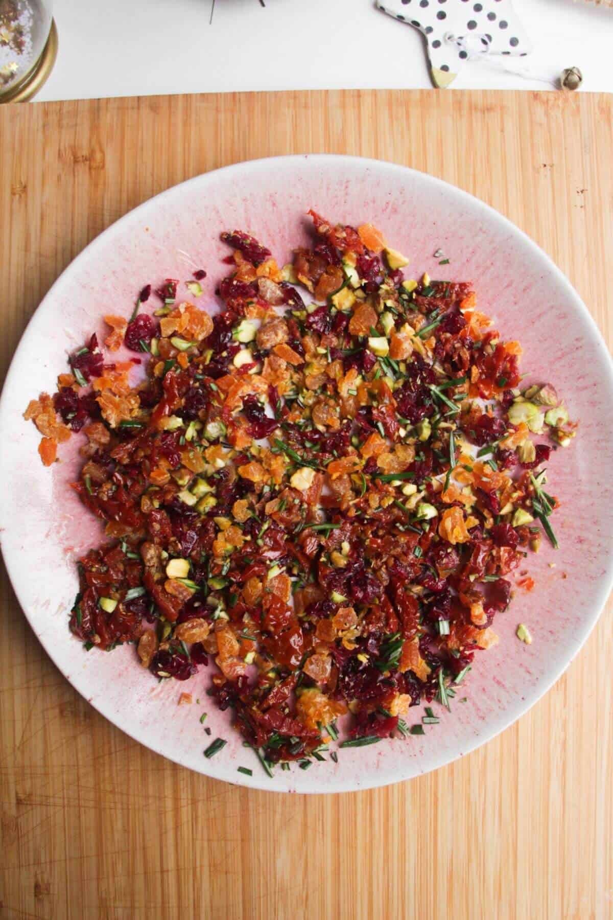 Christmas cheese ball toppings on a small pink plate.
