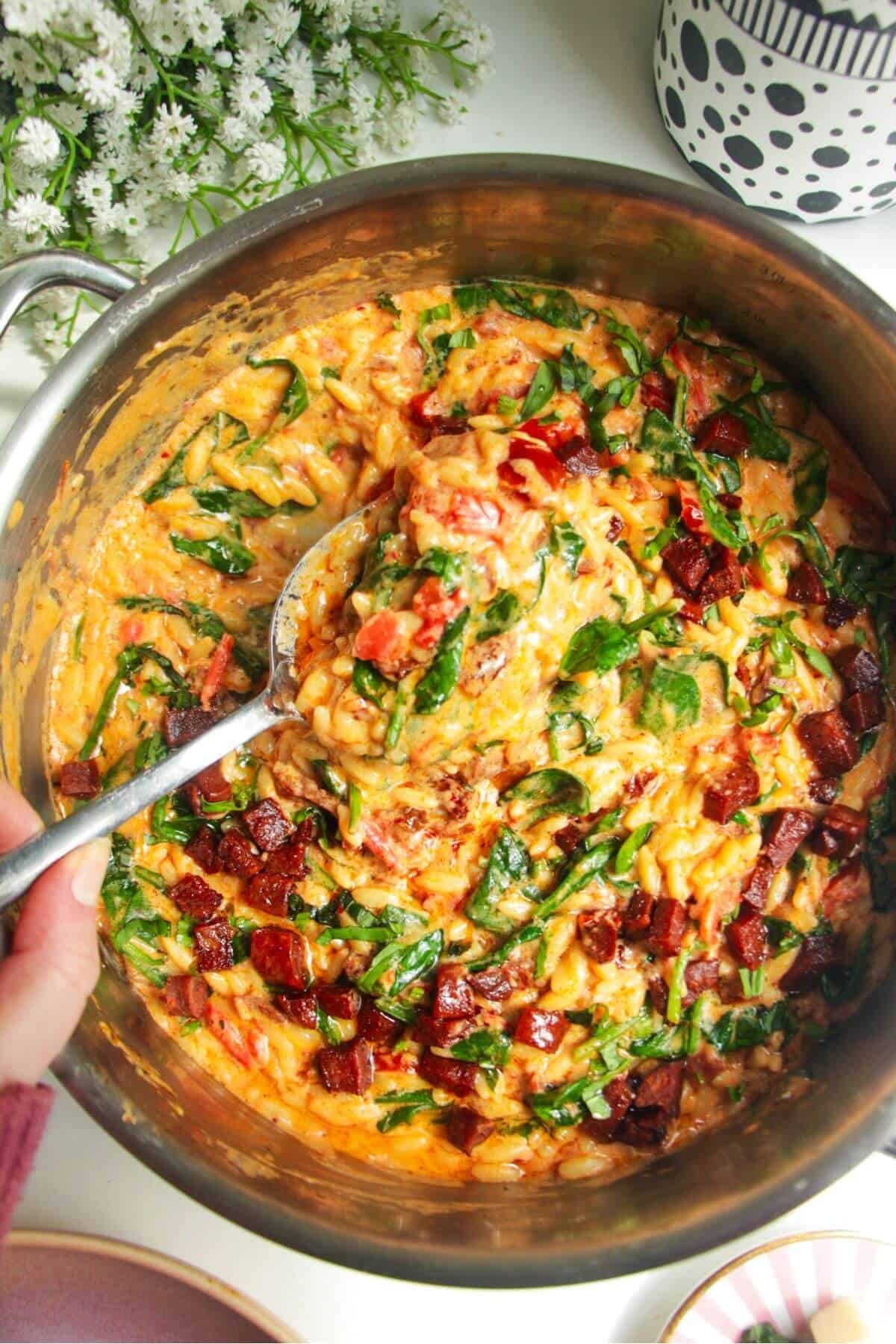 Creamy Marry Me orzo in a stainless steel pan with a silver spoon.