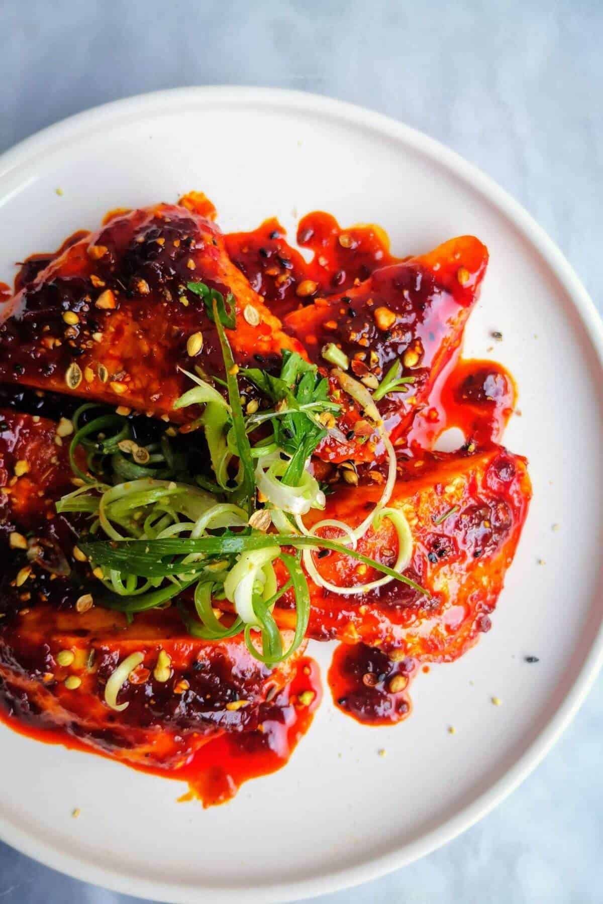 Halloumi triangles glazed with honey and harissa on a plate topped with spring onion and dukkah