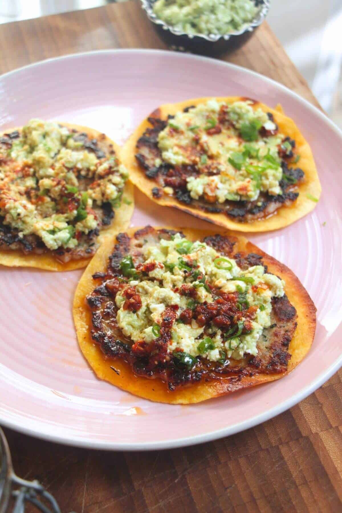 Three smash sausage tacos on a pink plate.
