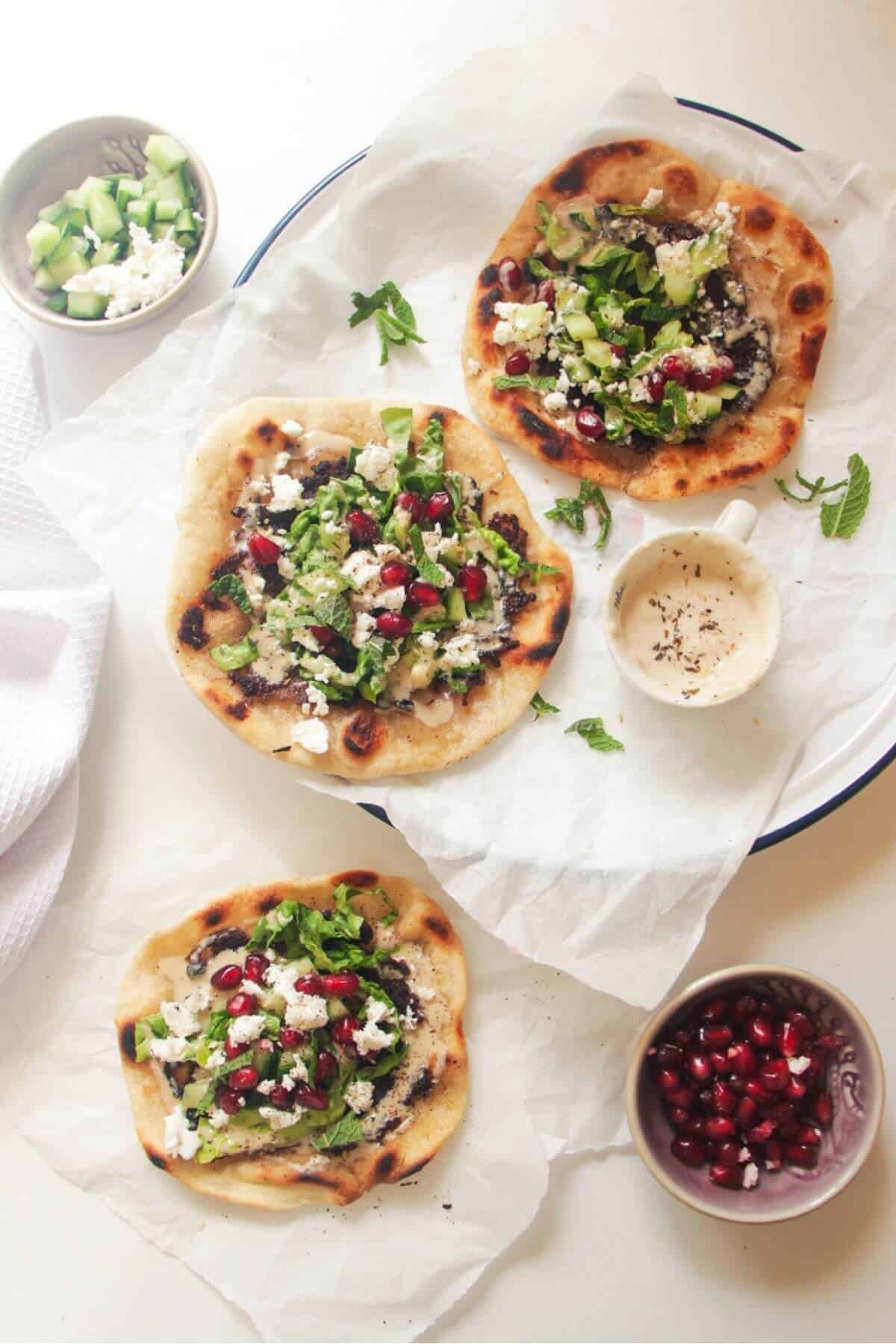Three smash kebab tacos on a white background with cucumber and sauce on the side.
