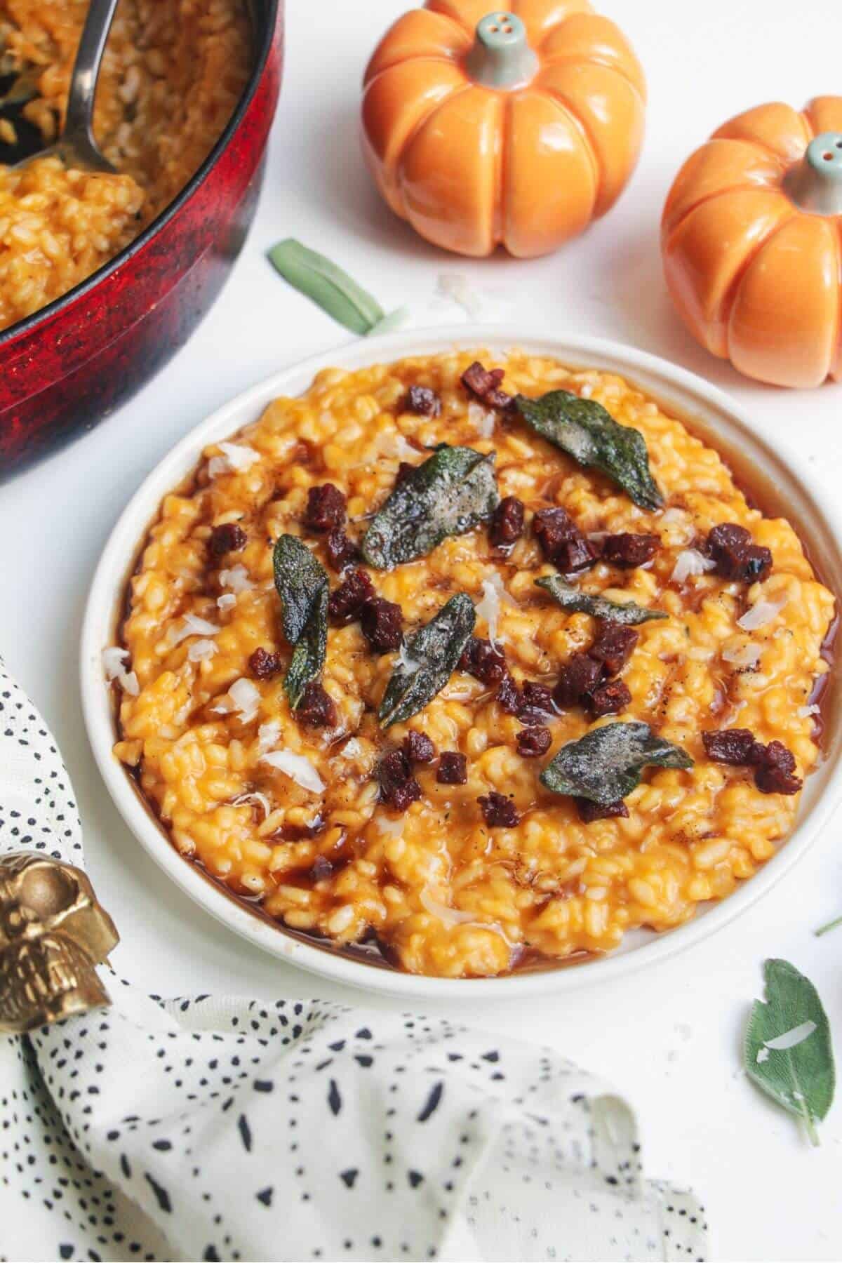 Butternut squash risotto on a small white plate, topped with sage brown butter and chorizo.