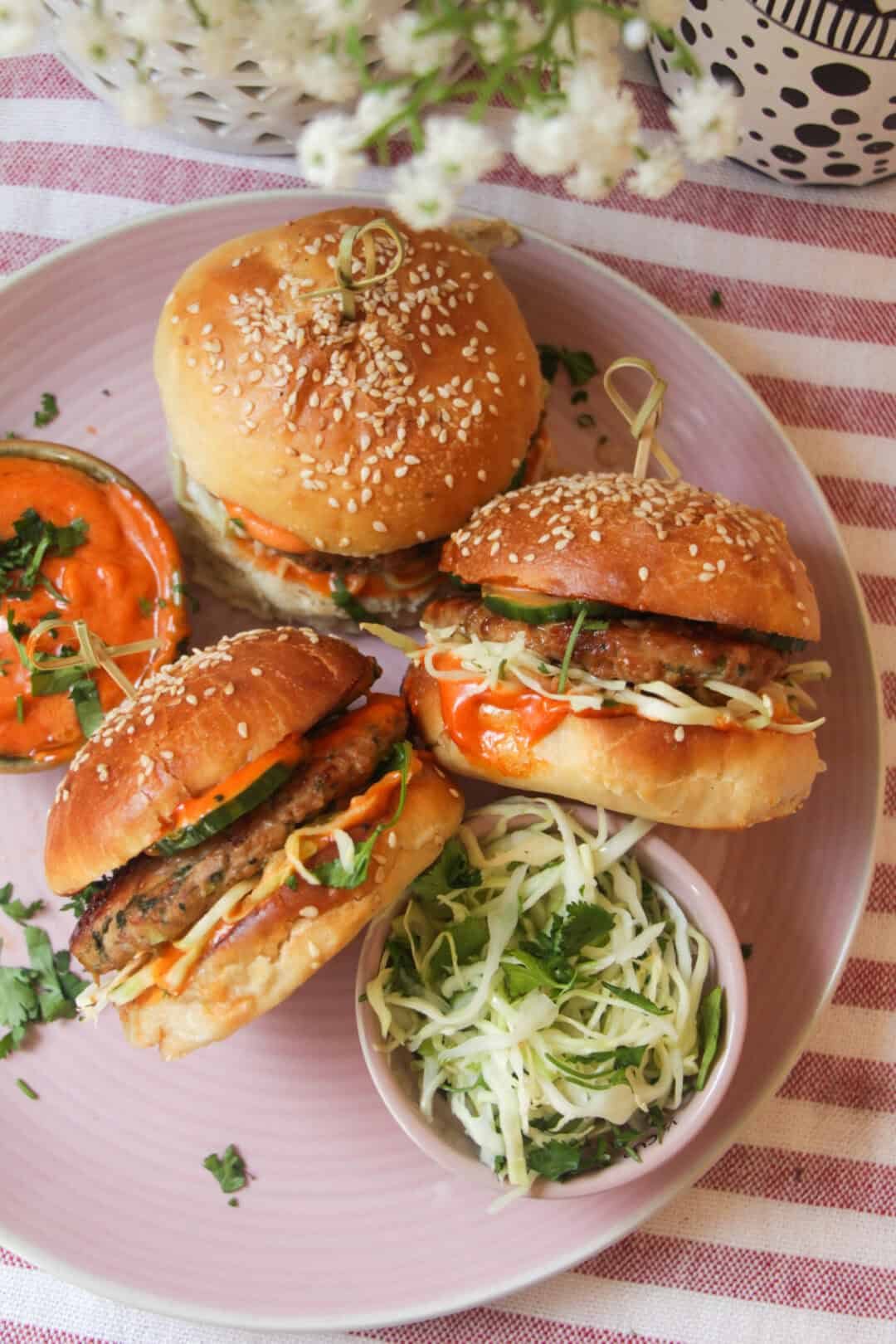 Three dumpling burgers on a pink plate.