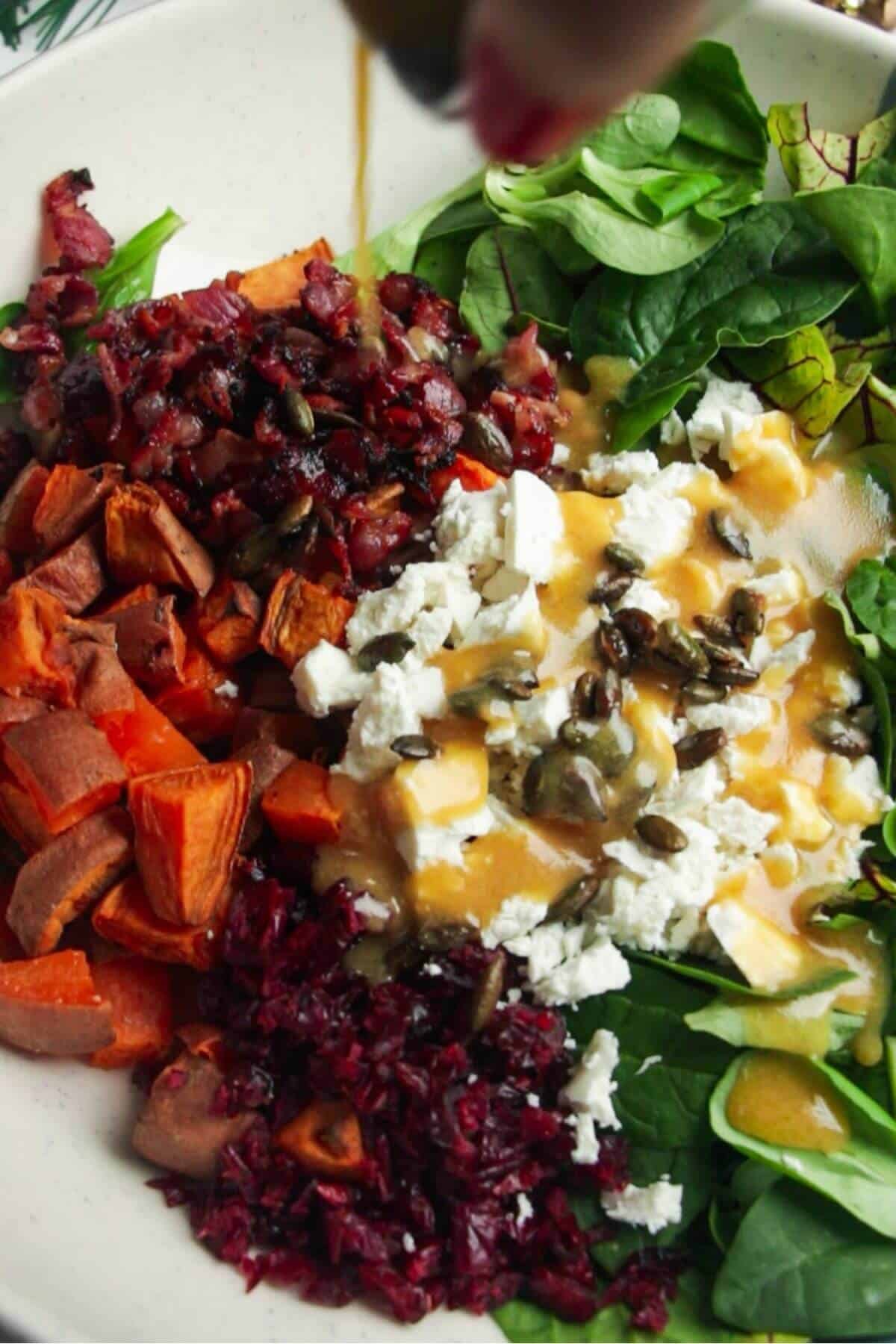 Pouring miso dressing over salad ingredients in a large white and blue bowl.
