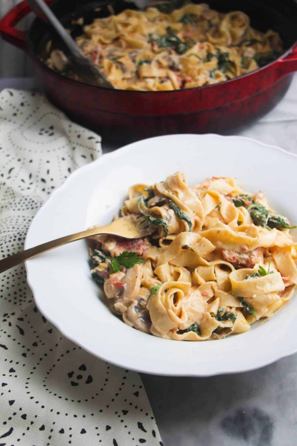 Close up of a bowl of creamy mushroom pasta, with a fork in it.