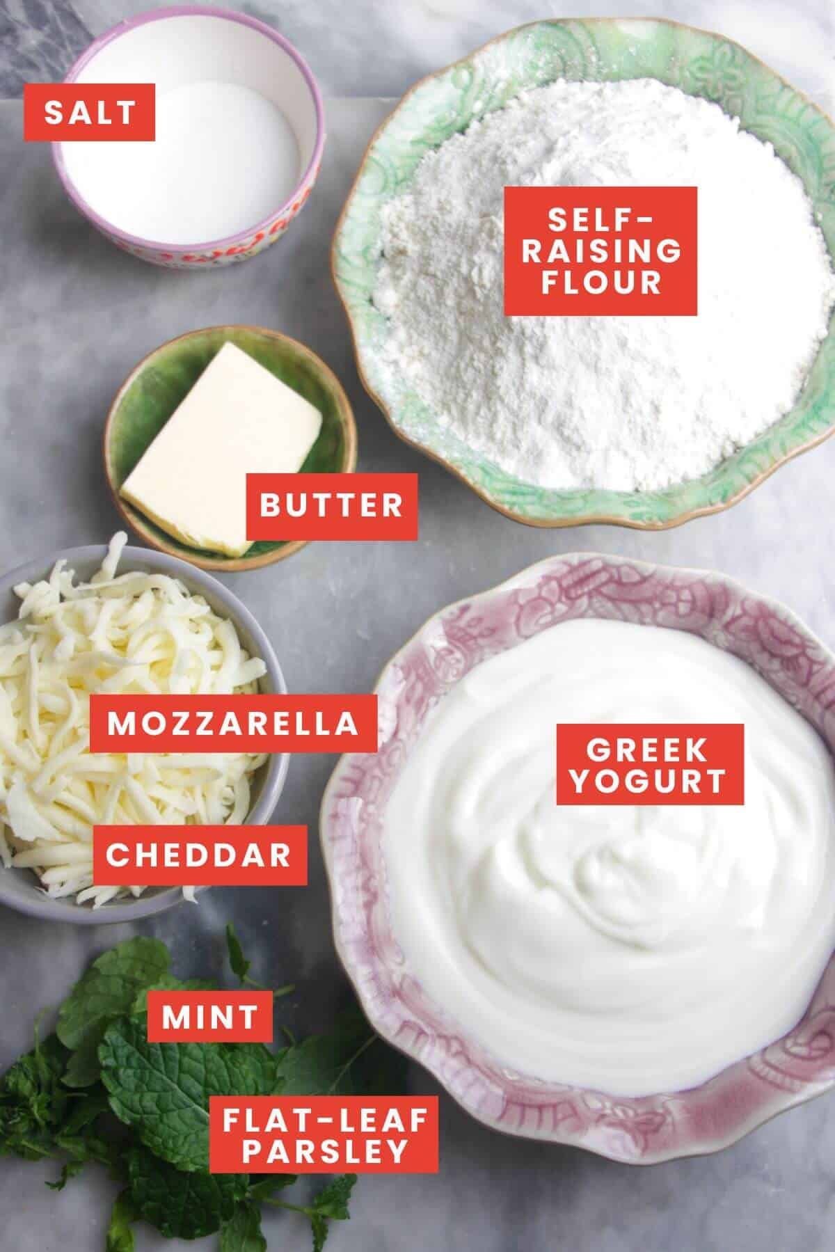 Ingredients for cheese naan laid out on a grey marble background and labelled.