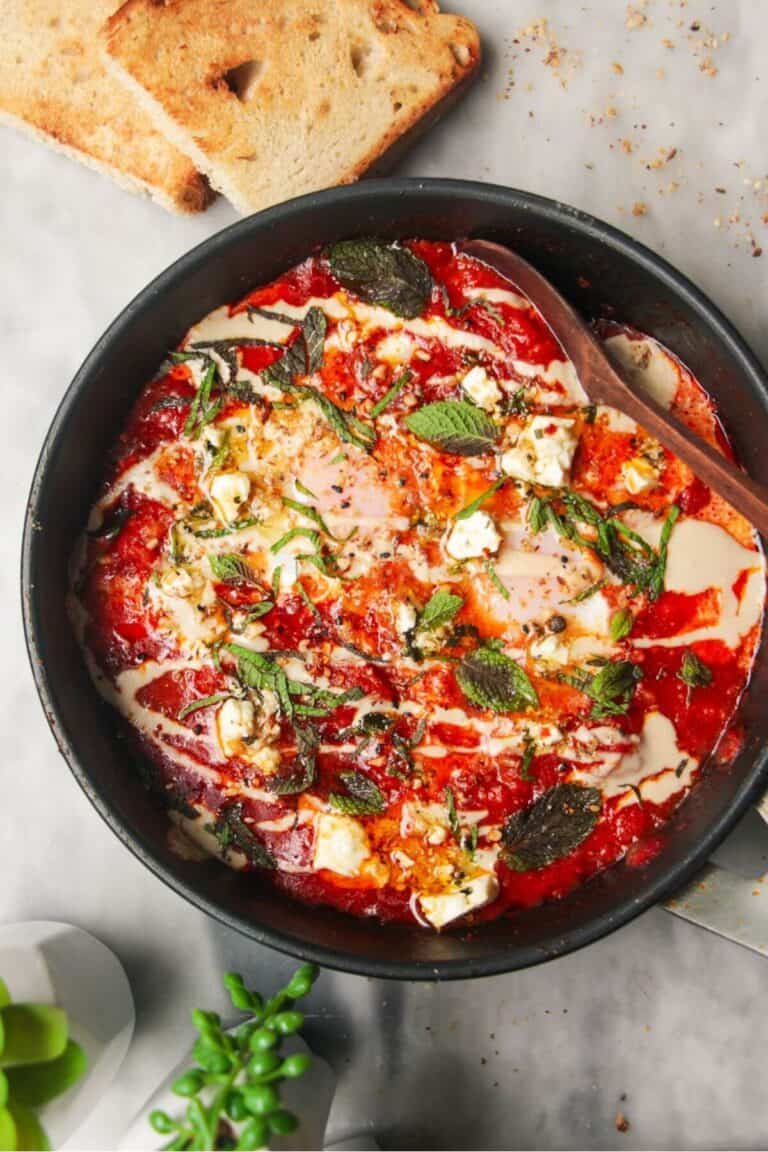 Shakshuka in a small black pan with toast on the side.