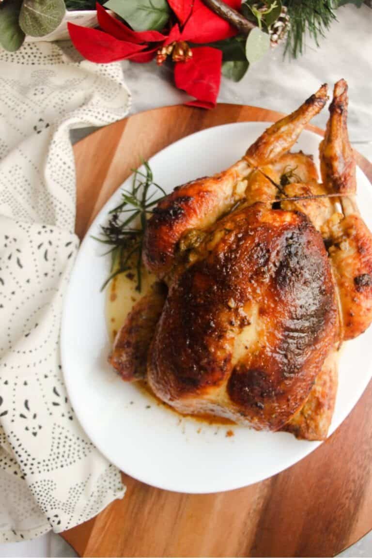 Close up view of golden brown roasted chicken on a white oval plat.