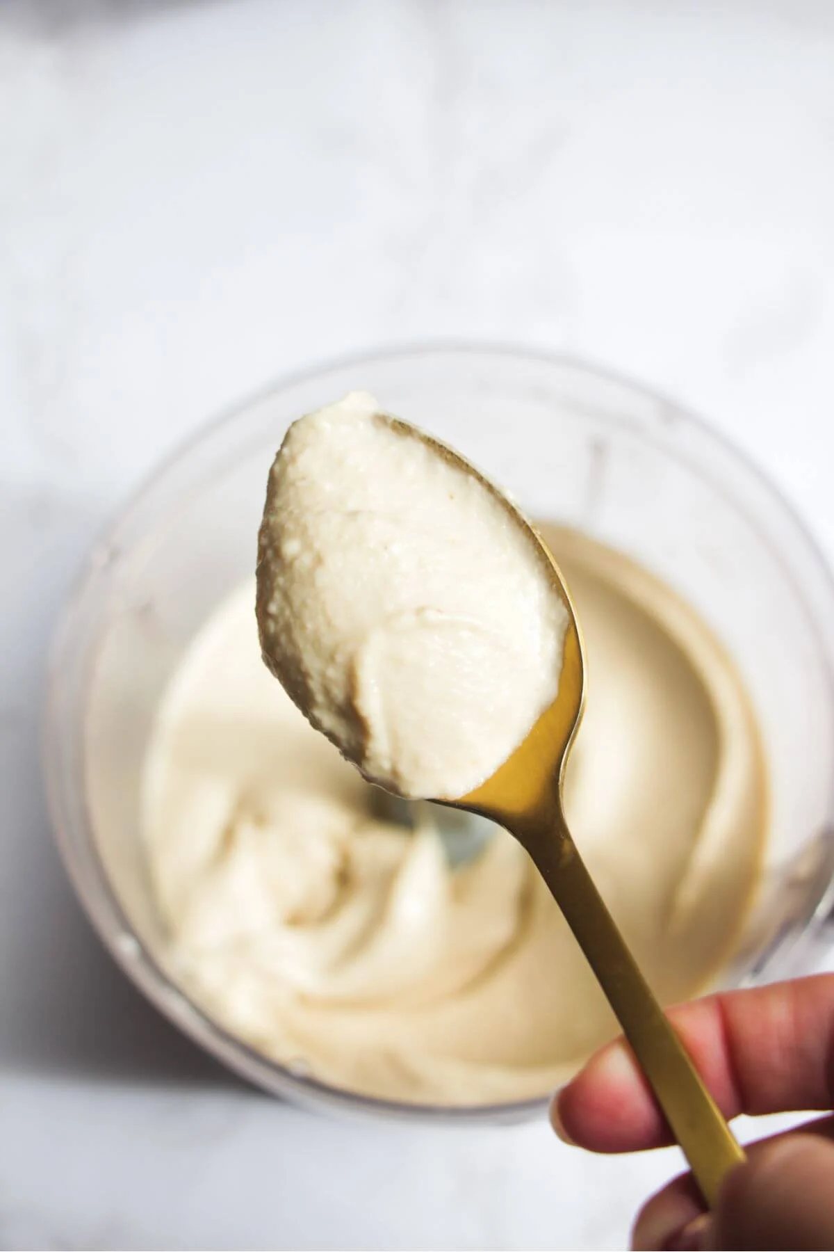 White bean dip on a gold spoon with more dip in the background.
