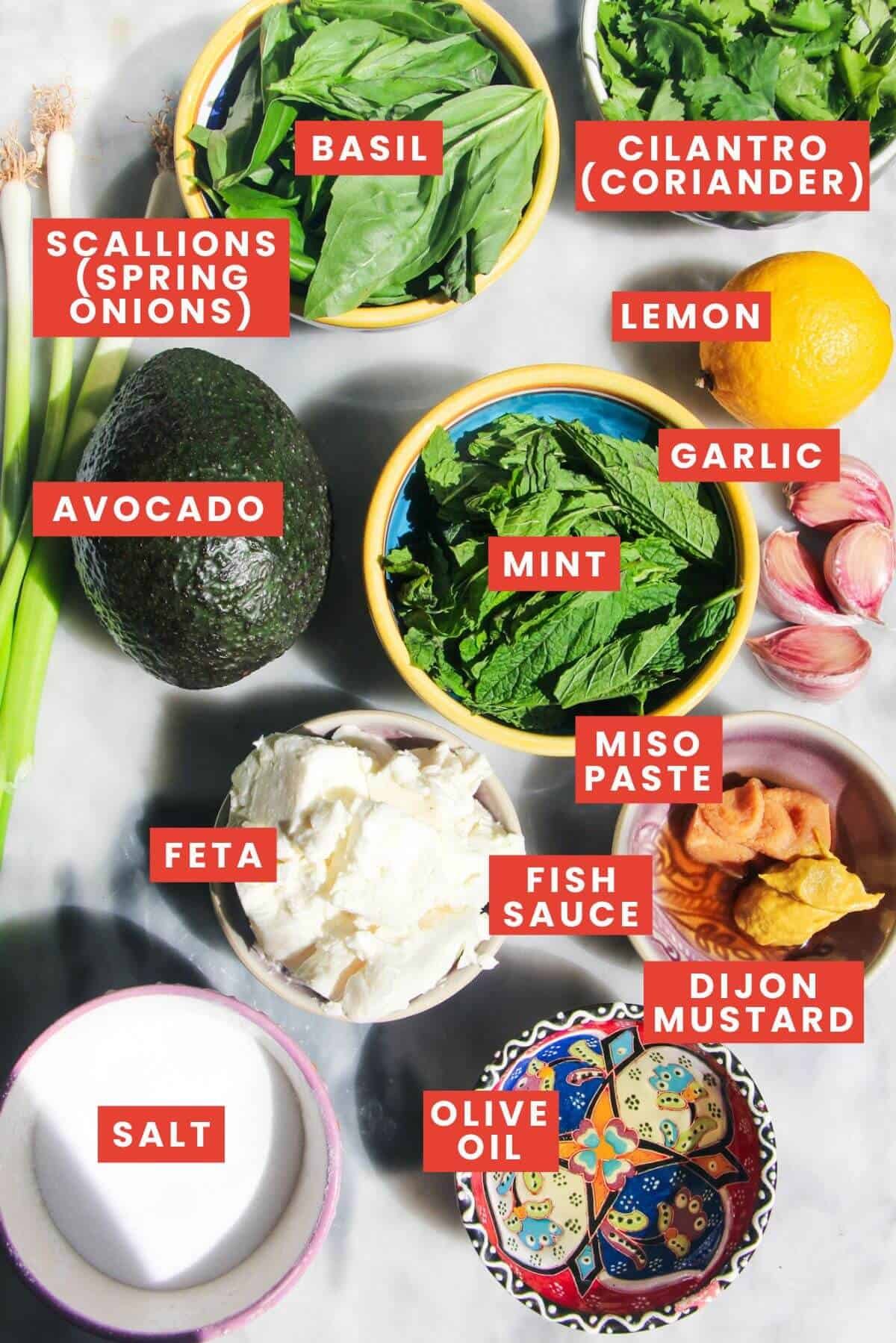 Ingredients for green goddess dip laid out on a grey marble background and labelled.
