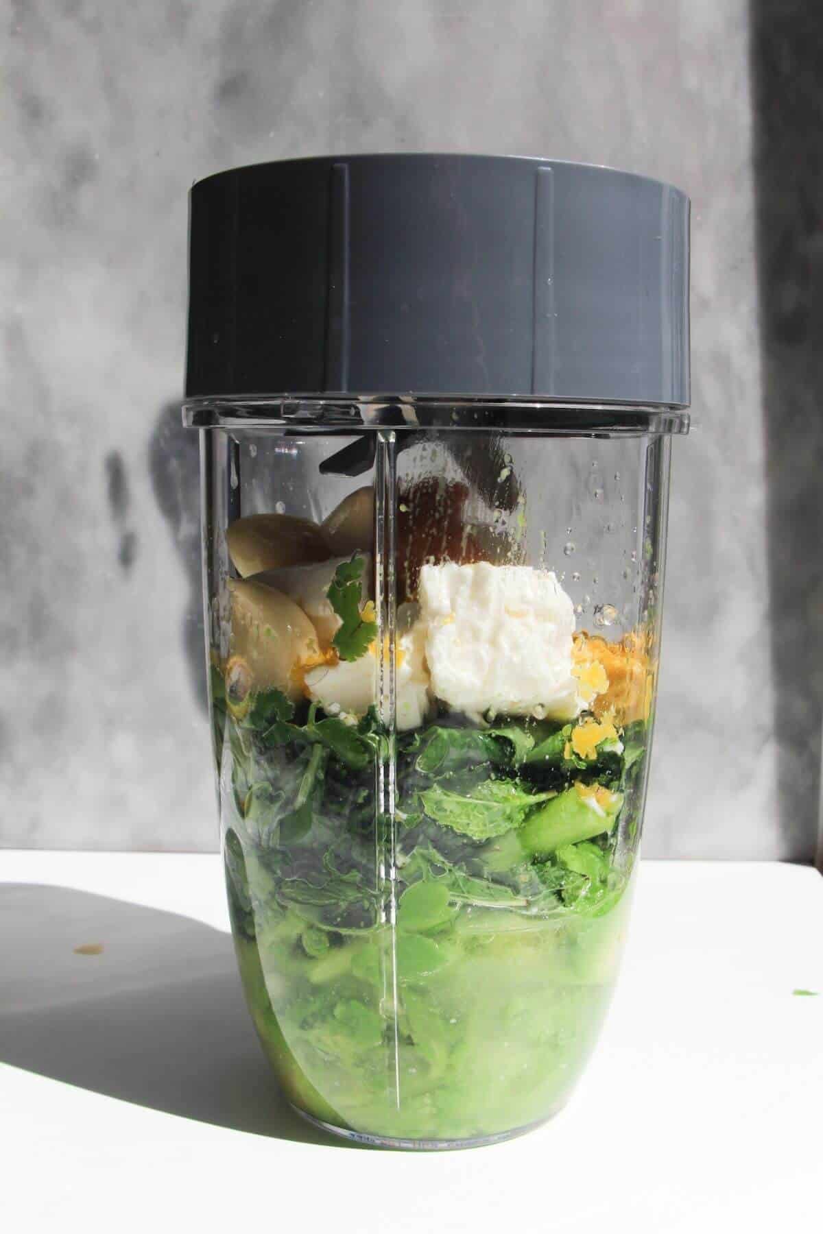 Green goddess dip ingredients in the bowl of a blender.