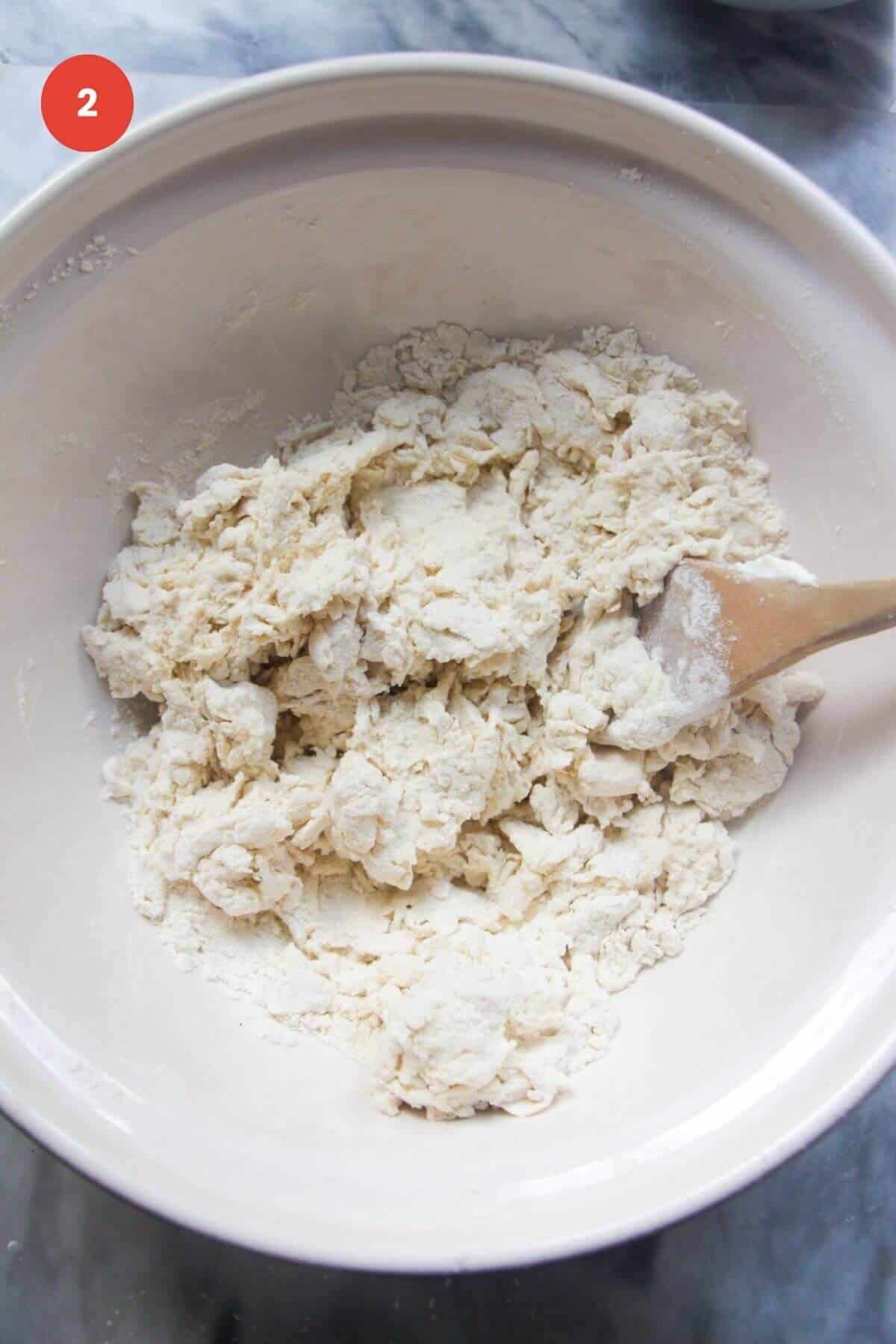 Shaggy flour and yogurt dough in a bowl with spatula.