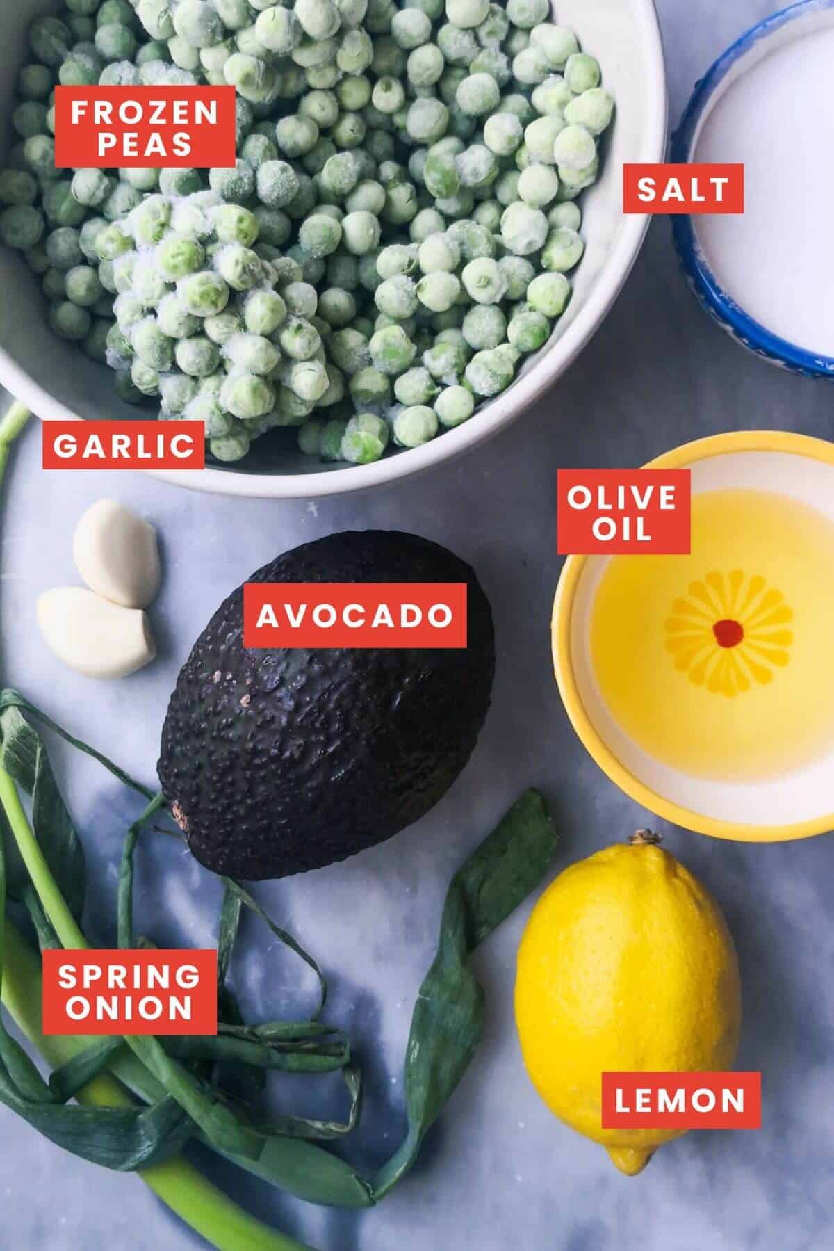 Ingredients for pea hummus with avocado laid out on a grey marble background.