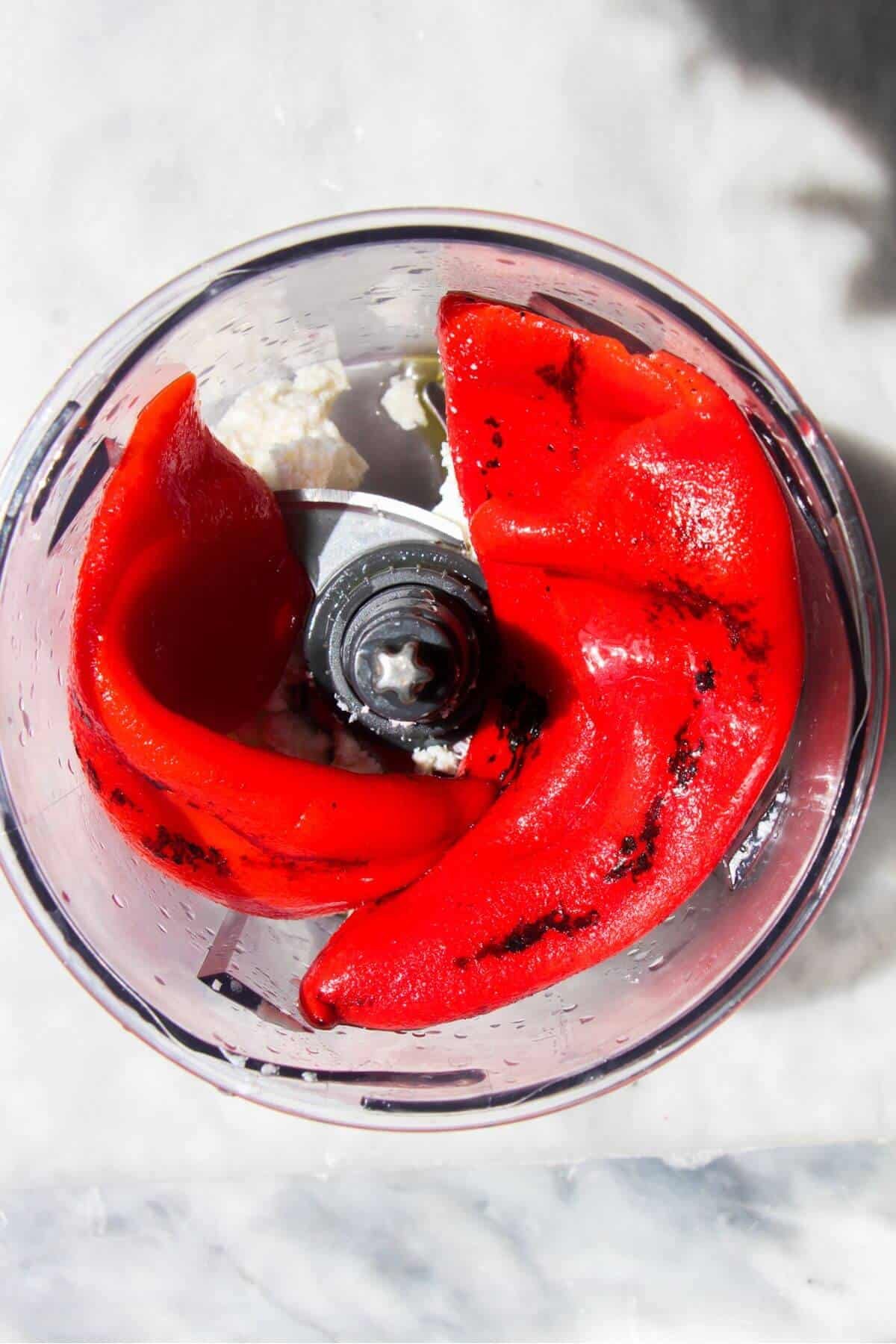 Red pepper and feta in a small food processor bowl.