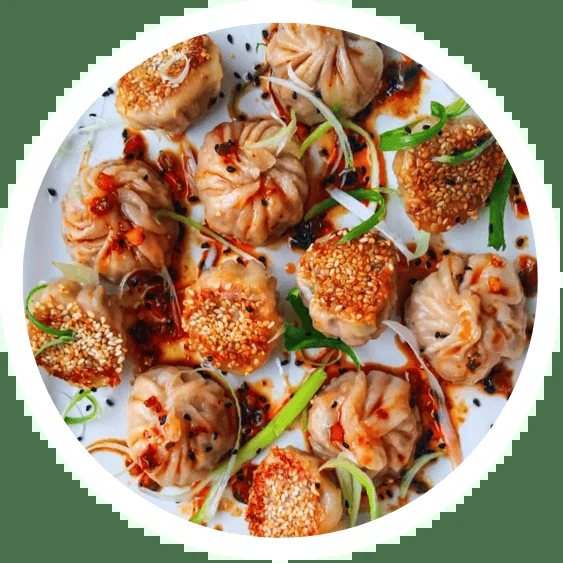 Crispy sesame crusted dumplings on a white plate with chilli oil and spring onion.