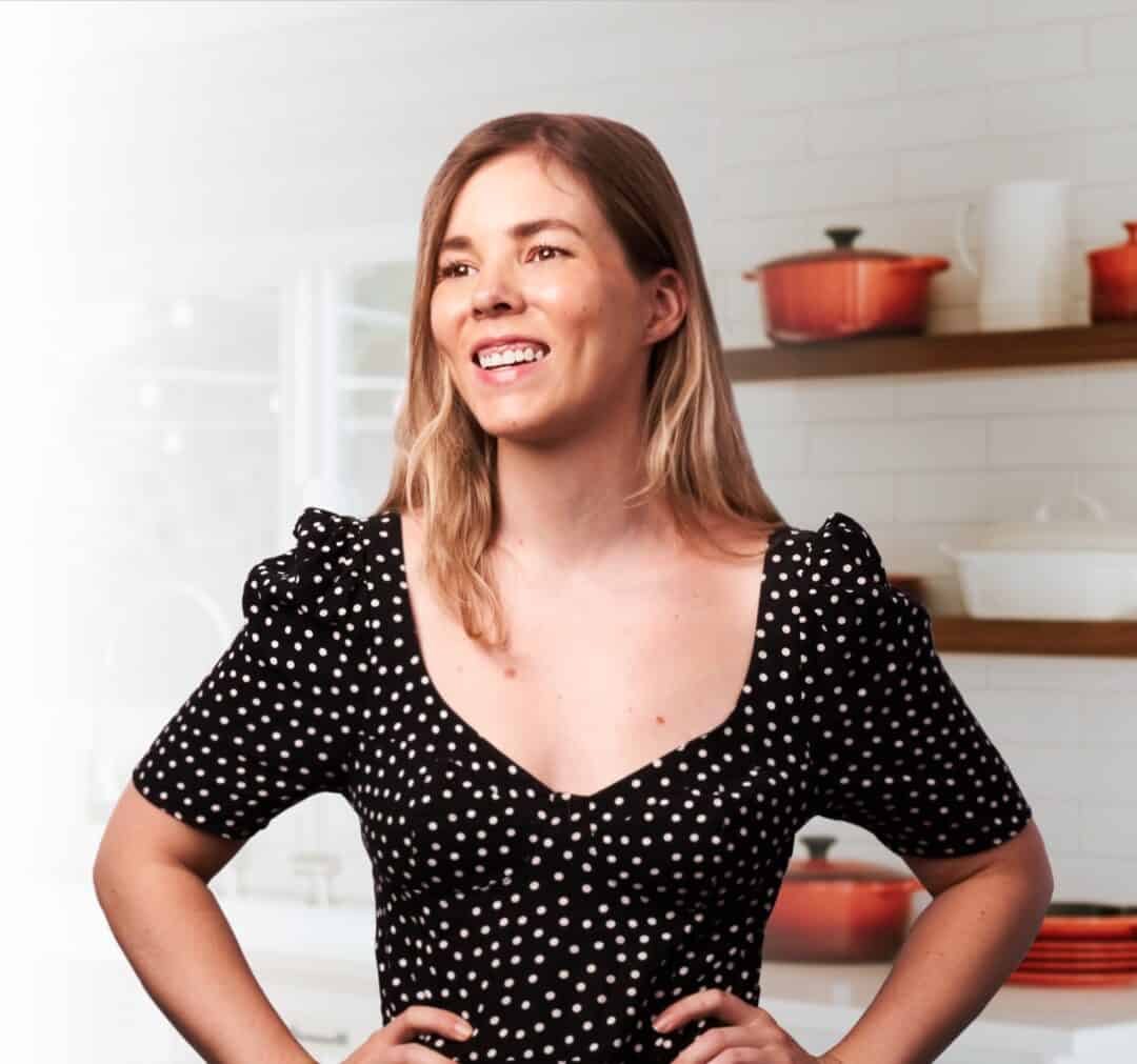Photo of Kate with hands on hips in a white kitchen.