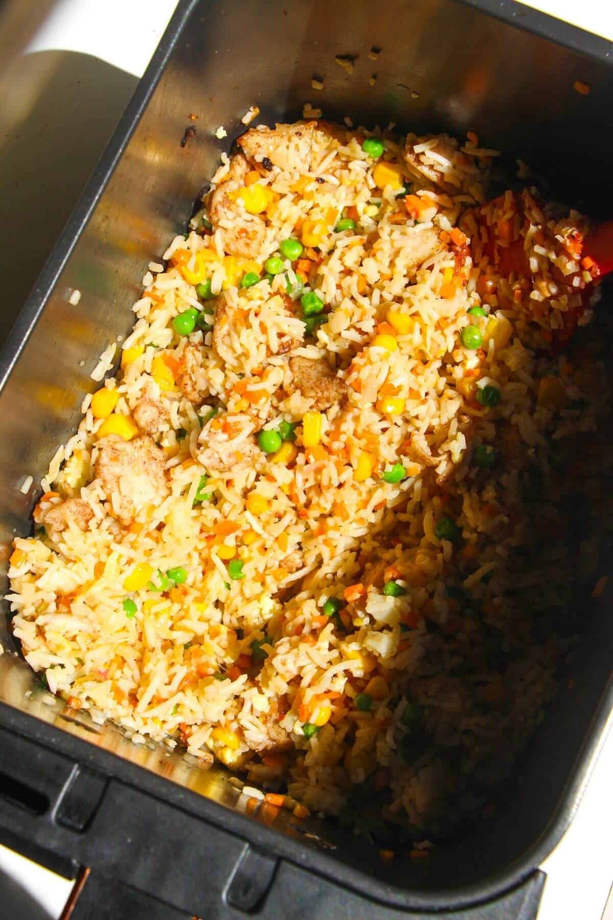 Par-cooked fried rice in air fryer basket.