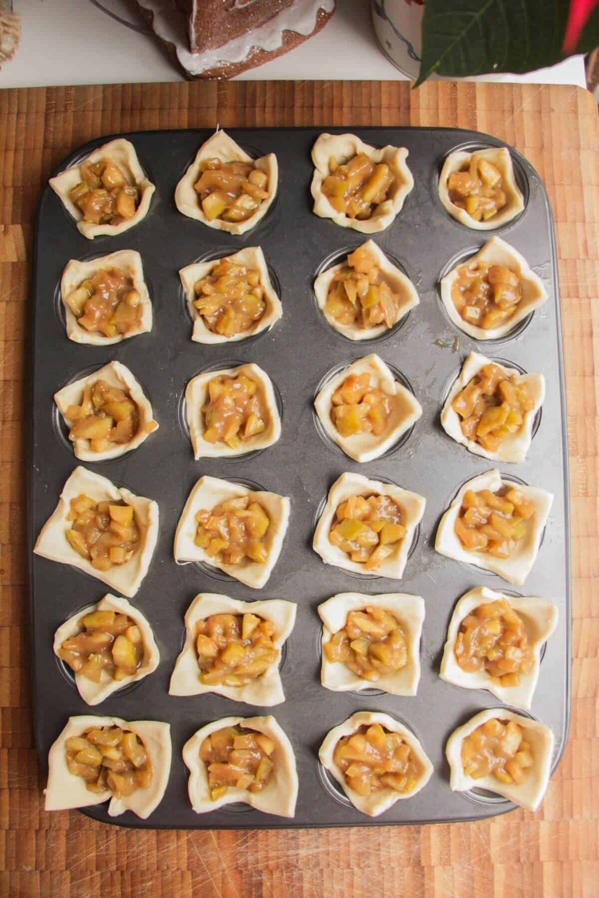 Apples inside pastry in a mini muffin tin.
