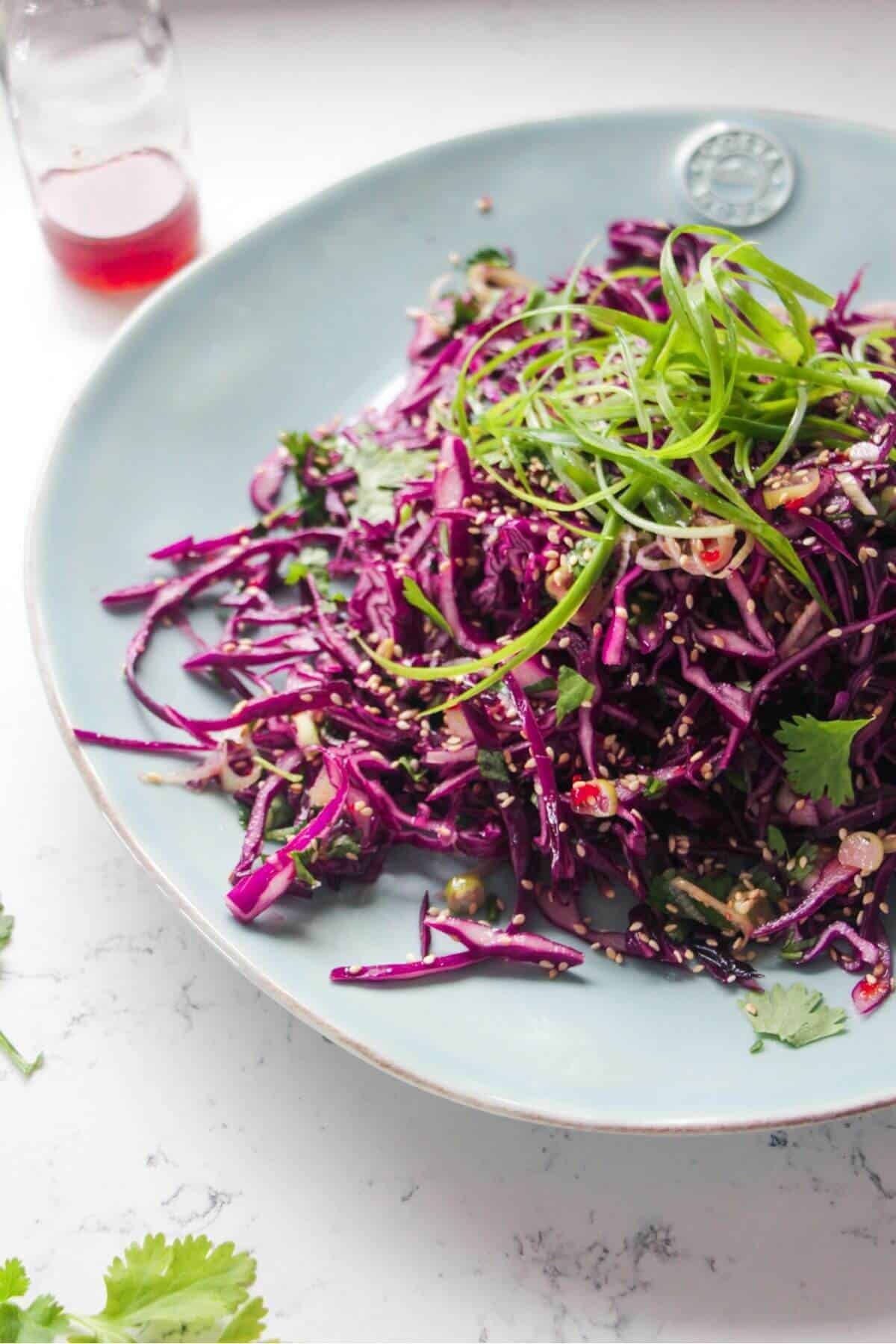 Close up of Asian salad on a large blue serving plate.