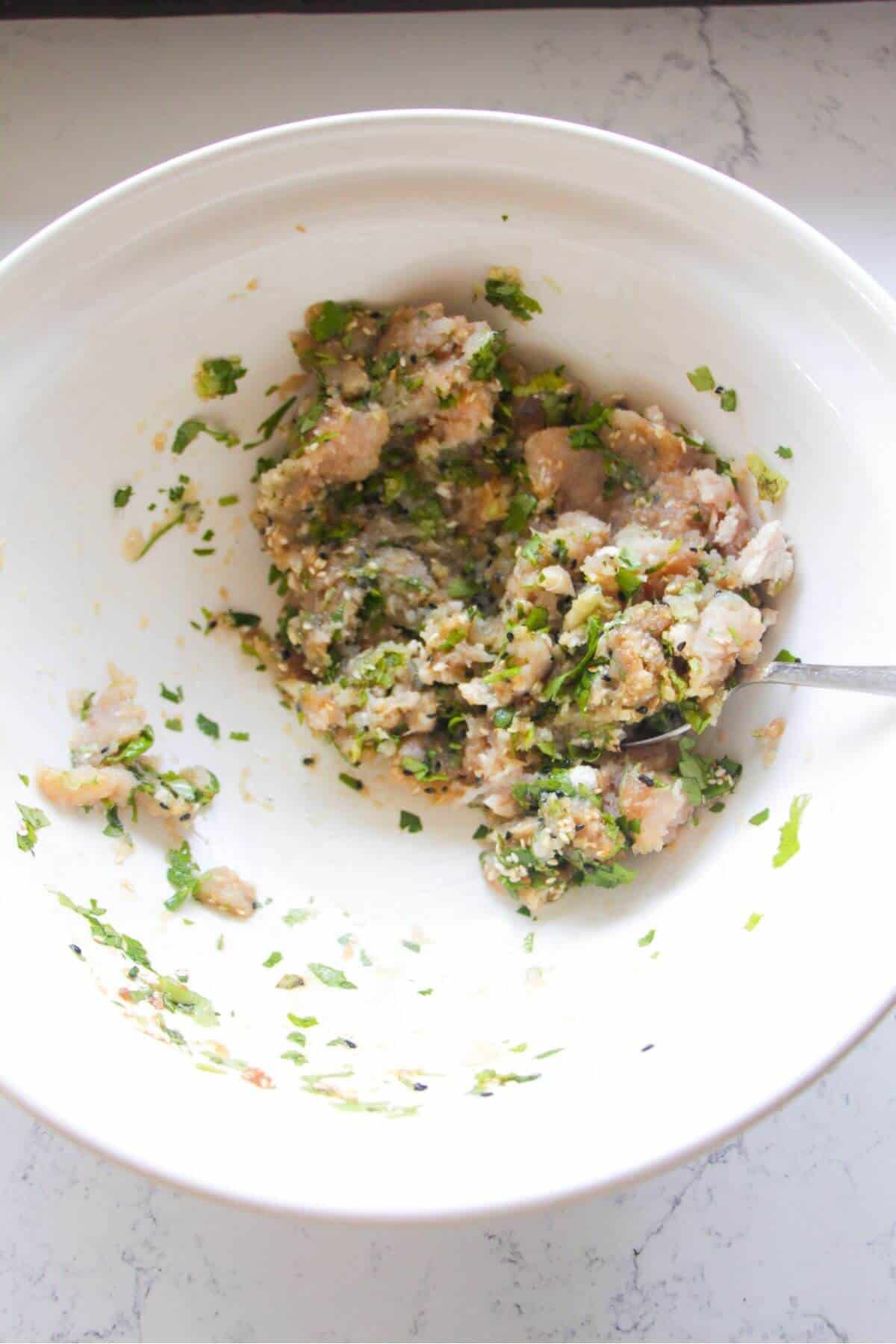 Chicken meatball mixtue in a large white bowl.
