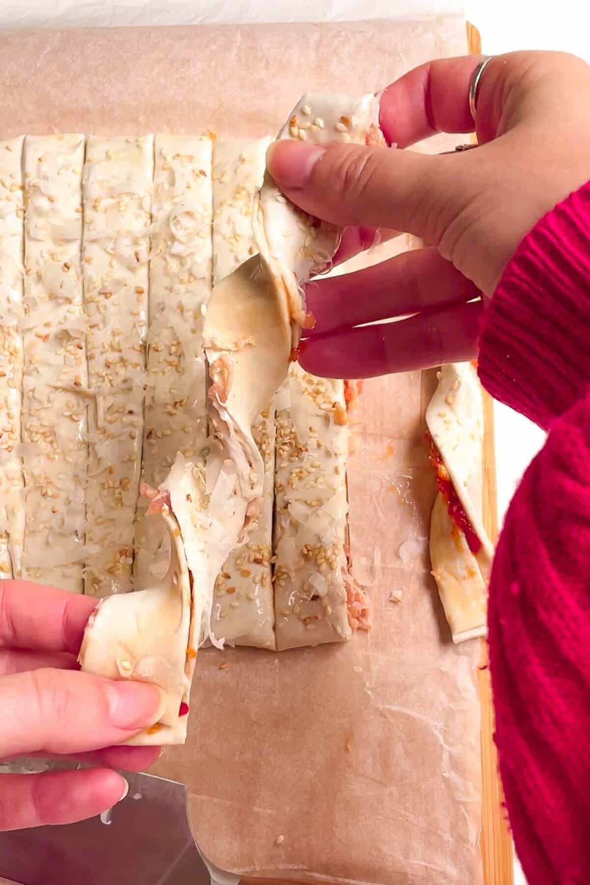 Holding an unbaked bacon blue cheese pastry twist.