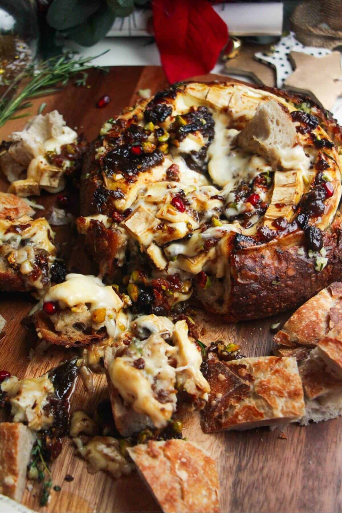 Gooey baked brie cheese oozing out of bread on a wooden board.