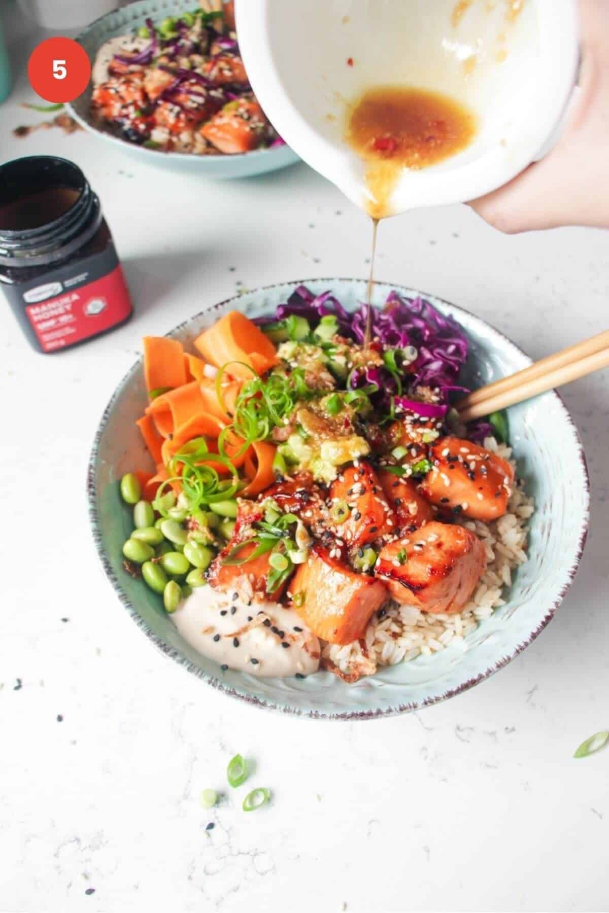 Pouring honey miso dressing on top of salmon poke bowl.