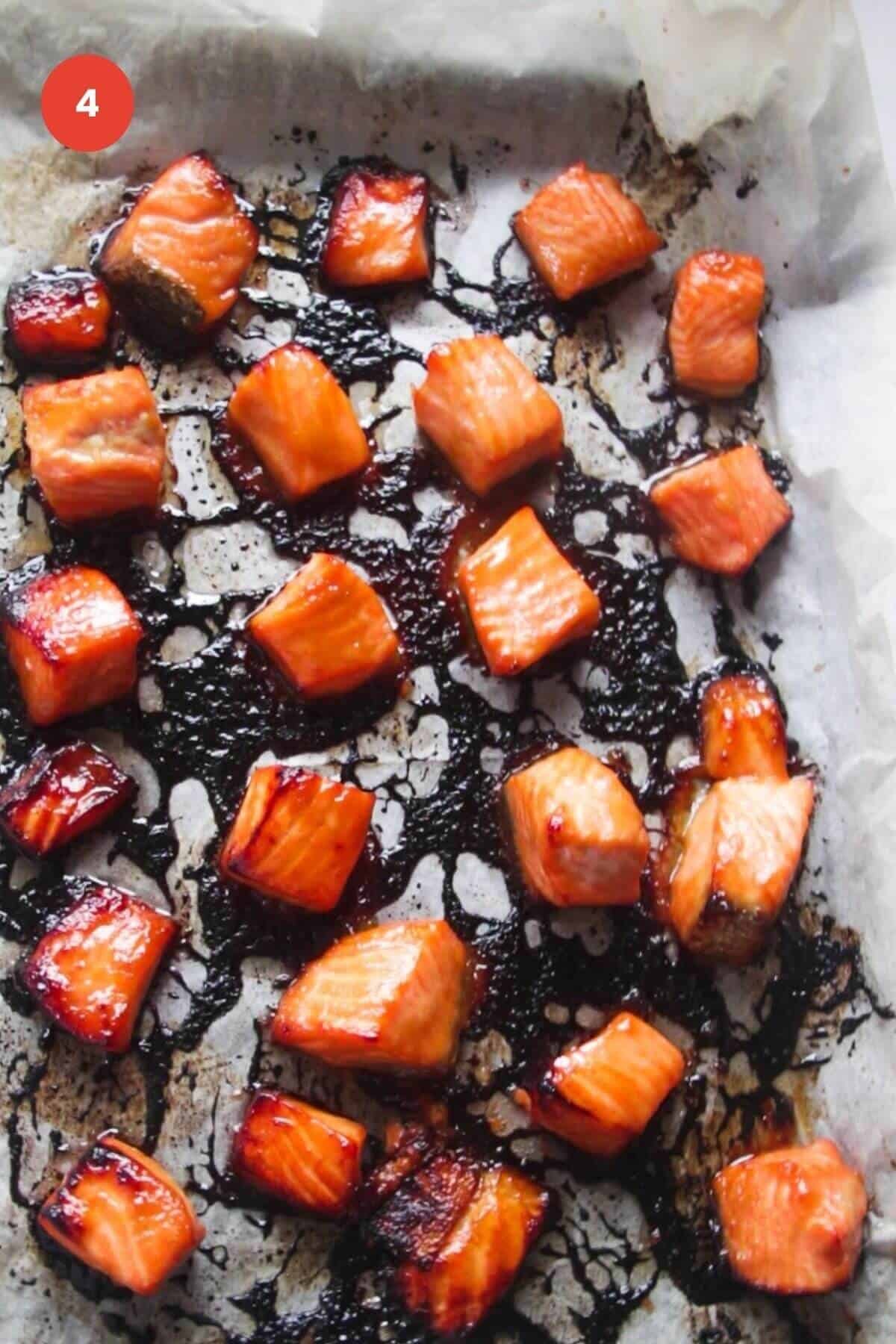 Charred baked salmon pieces on a sheet pan.