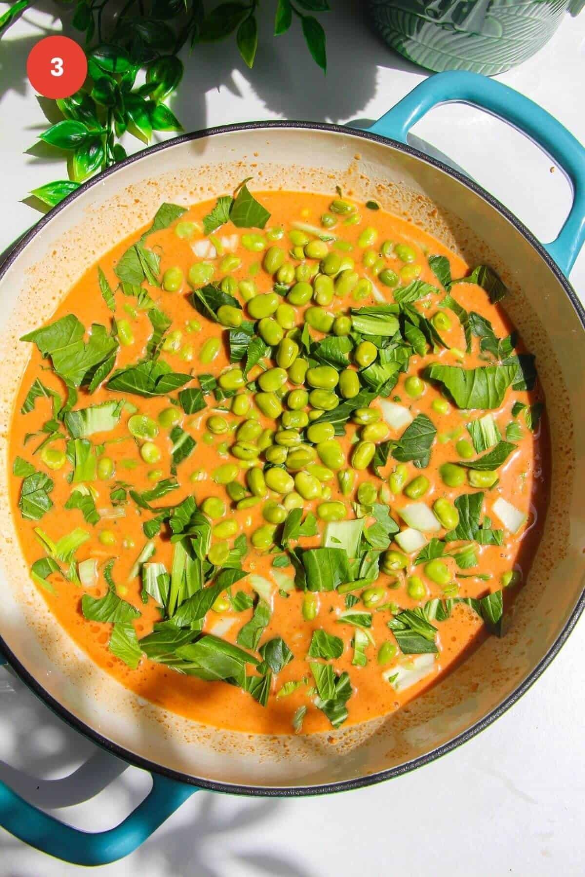 Edamame and bok choy scattered into sauce in pan.