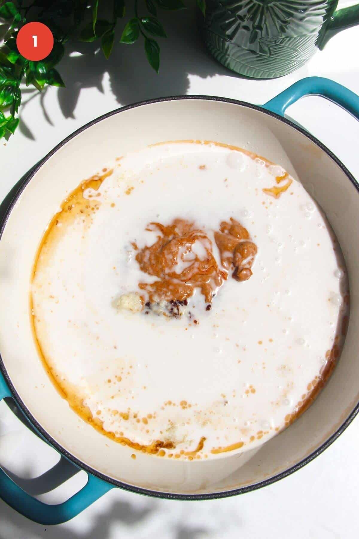 Coconut milk and other sauce ingredients in white skillet.