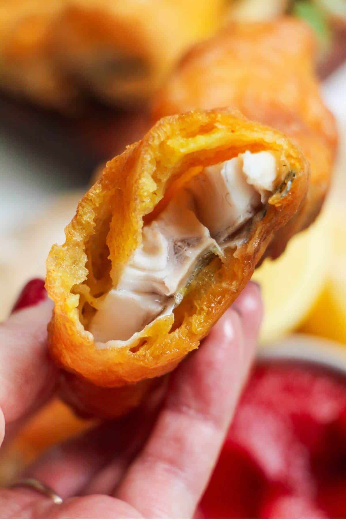Holding up a broken piece of beer battered fish so you can see inside.