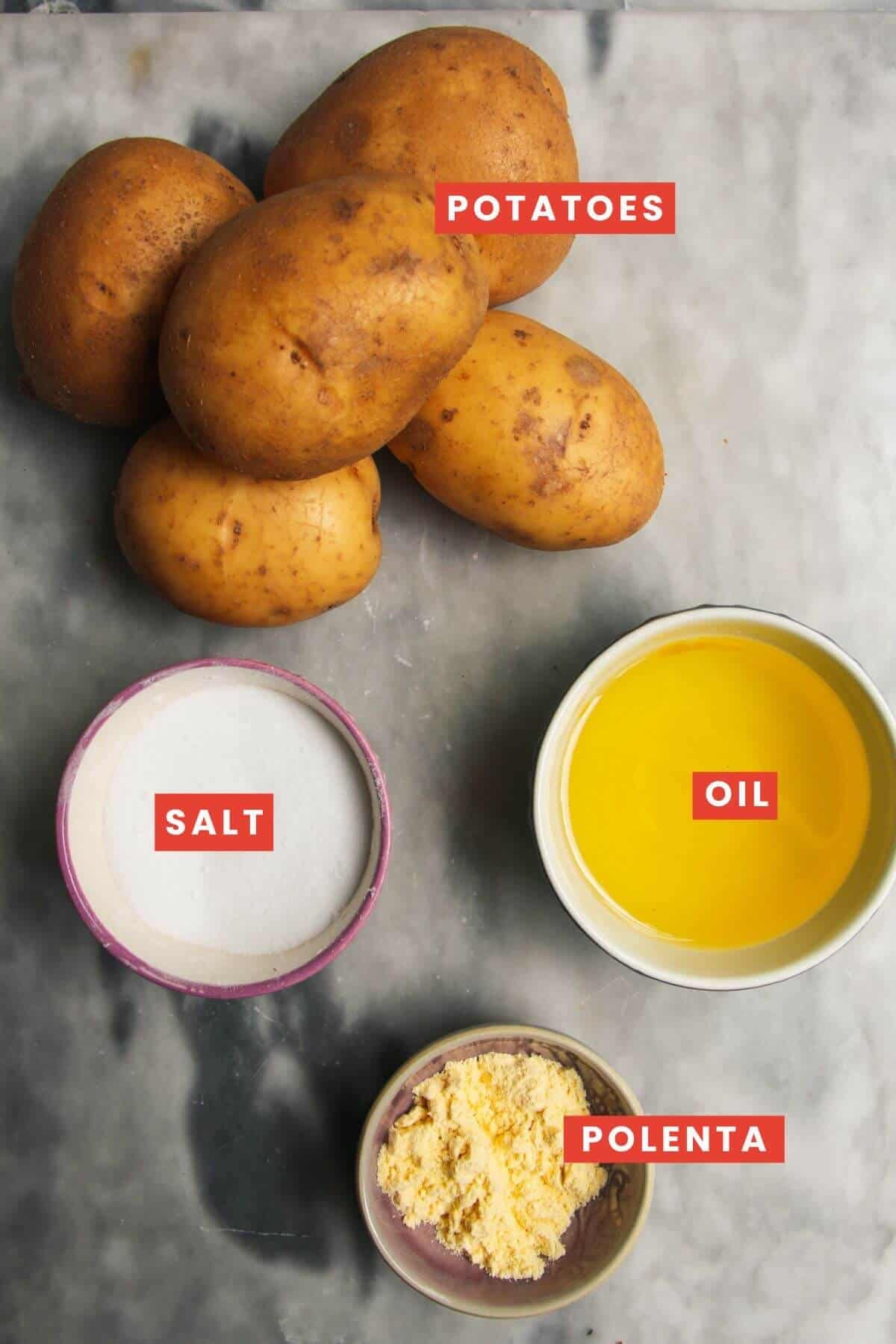 Ingredients for oven fries laid out on a grey marble background.