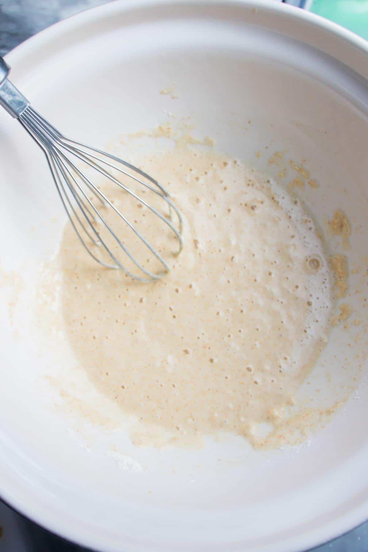 Whisking batter in a large white mixing bowl.