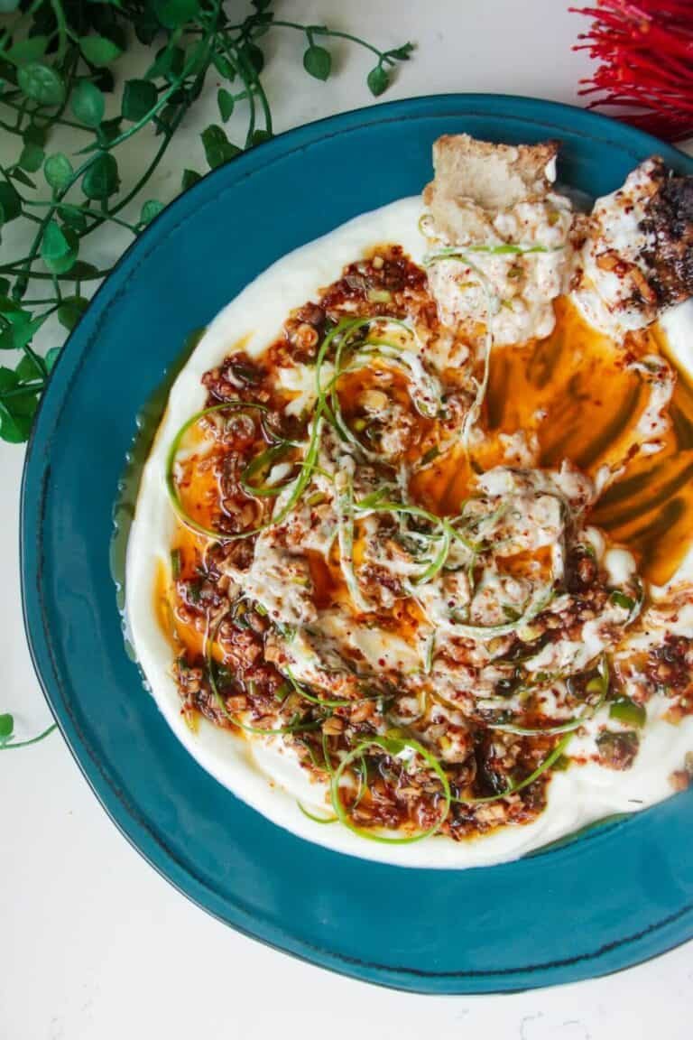 Sizzling oil on top of creamy Greek yogurt on a teal plate.