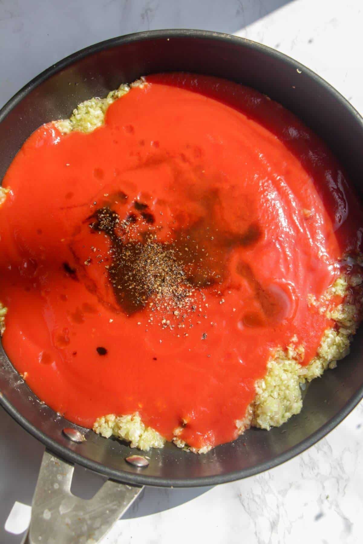 Tomato passata, Worcestershire sauce, Tabasco and black pepper added to garlic, onion and celery in a small pan.