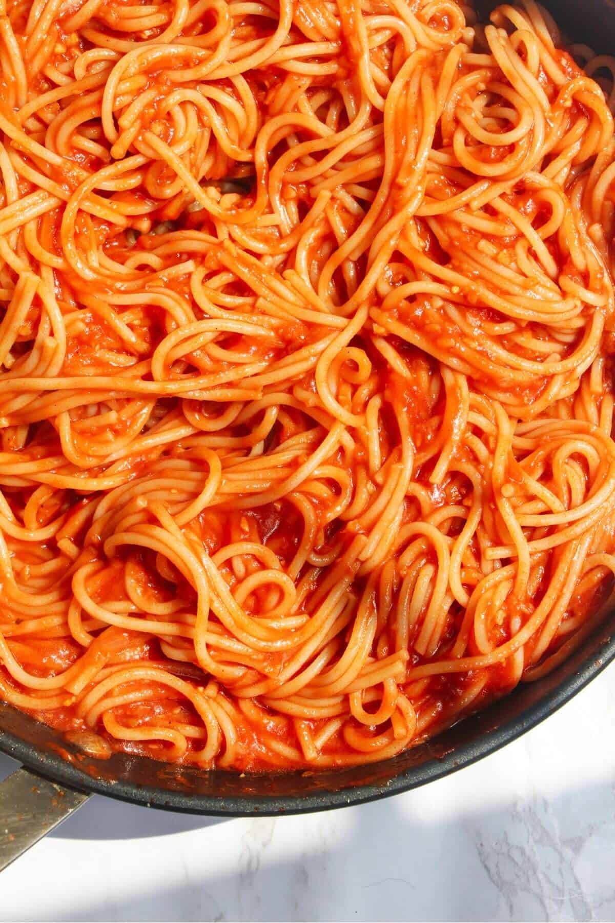 Spaghetti mixed with bloody mary pasta sauce in a small pan.