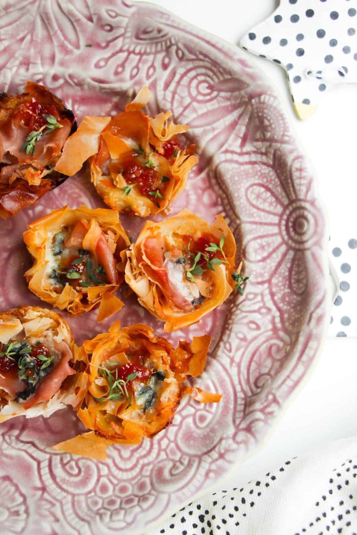 Baked blue cheese, prosciutto, sweet chilli bites on a small pink plate.