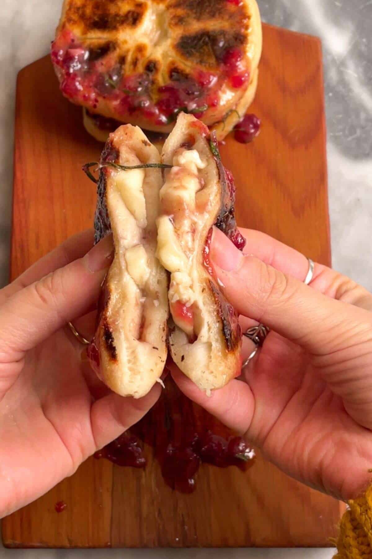 Hands squeezing brie stuffed flatbread.