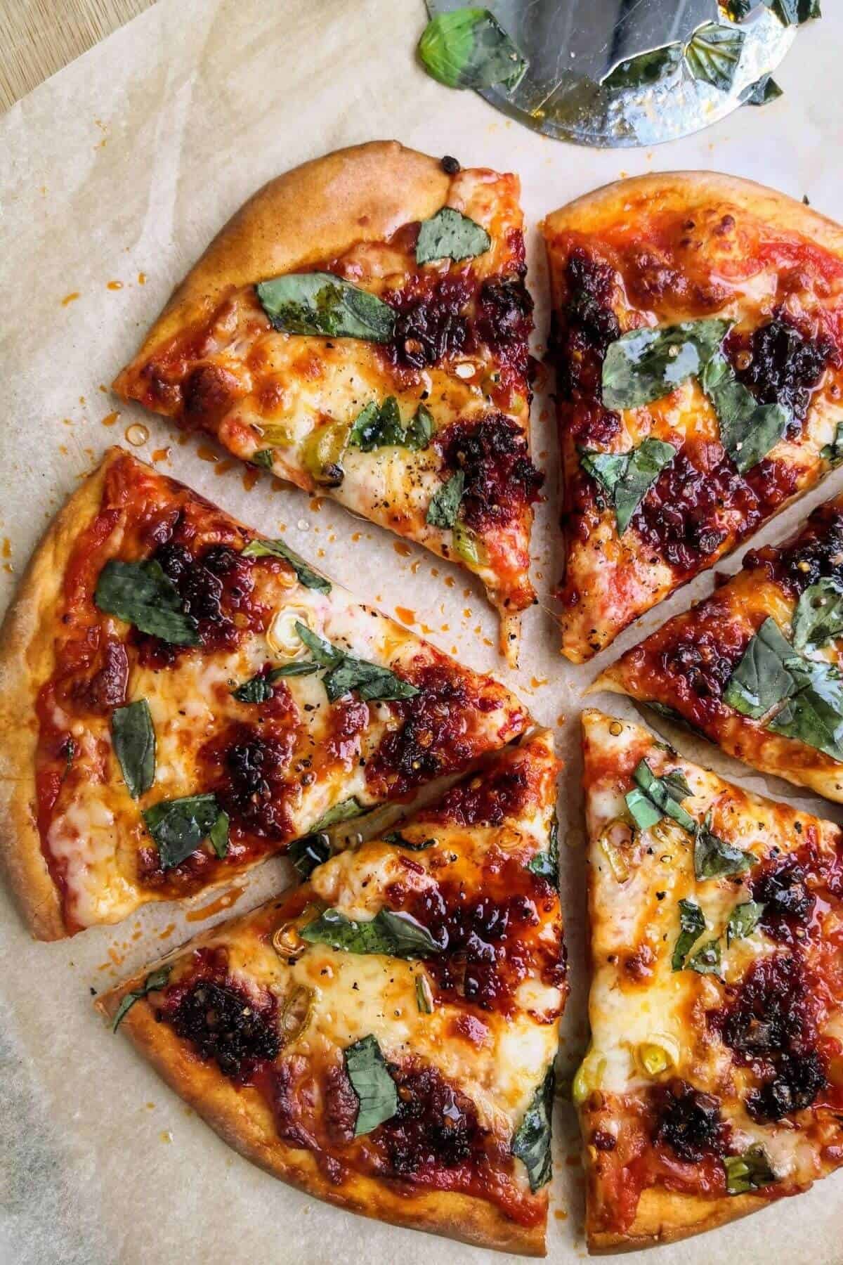 Nduja, spring onion and honey pizza sliced on a board.