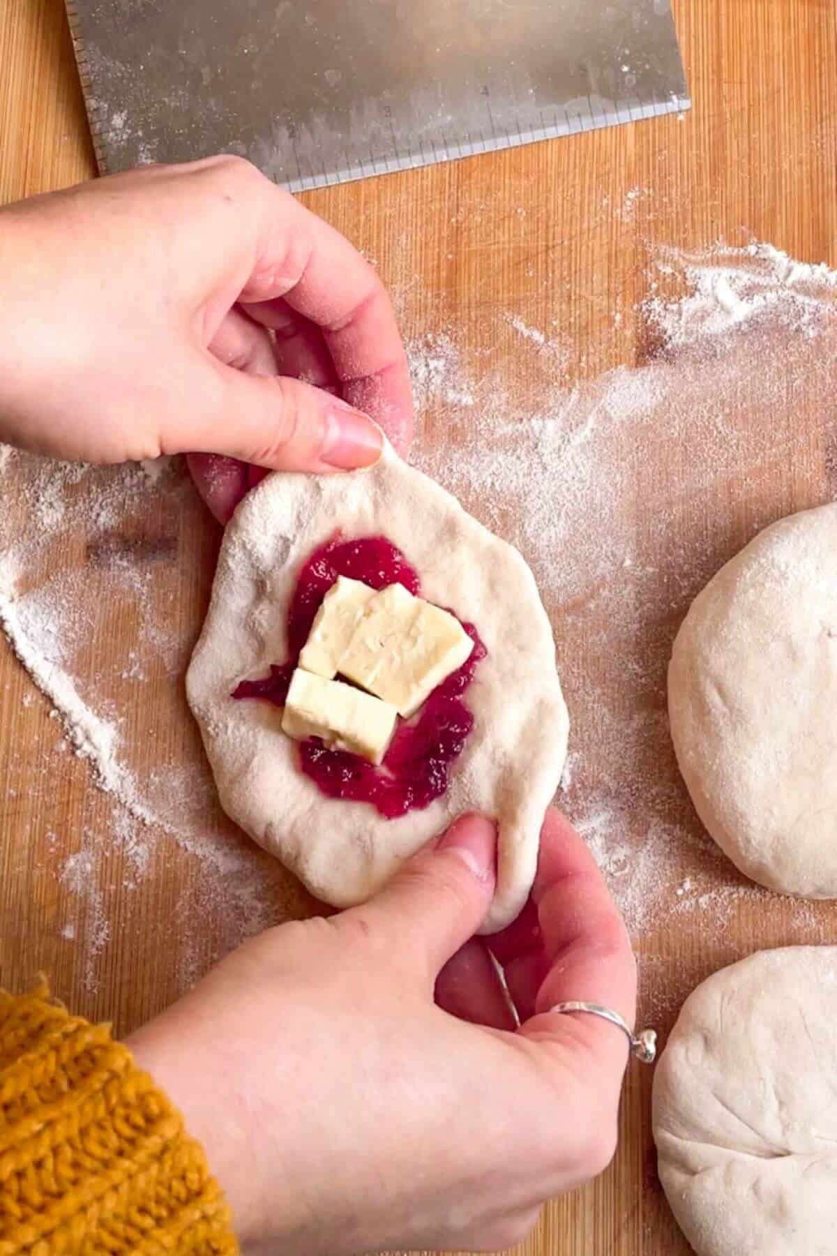 Cubes of brie on top of cranberry sauce on piece of dough.
