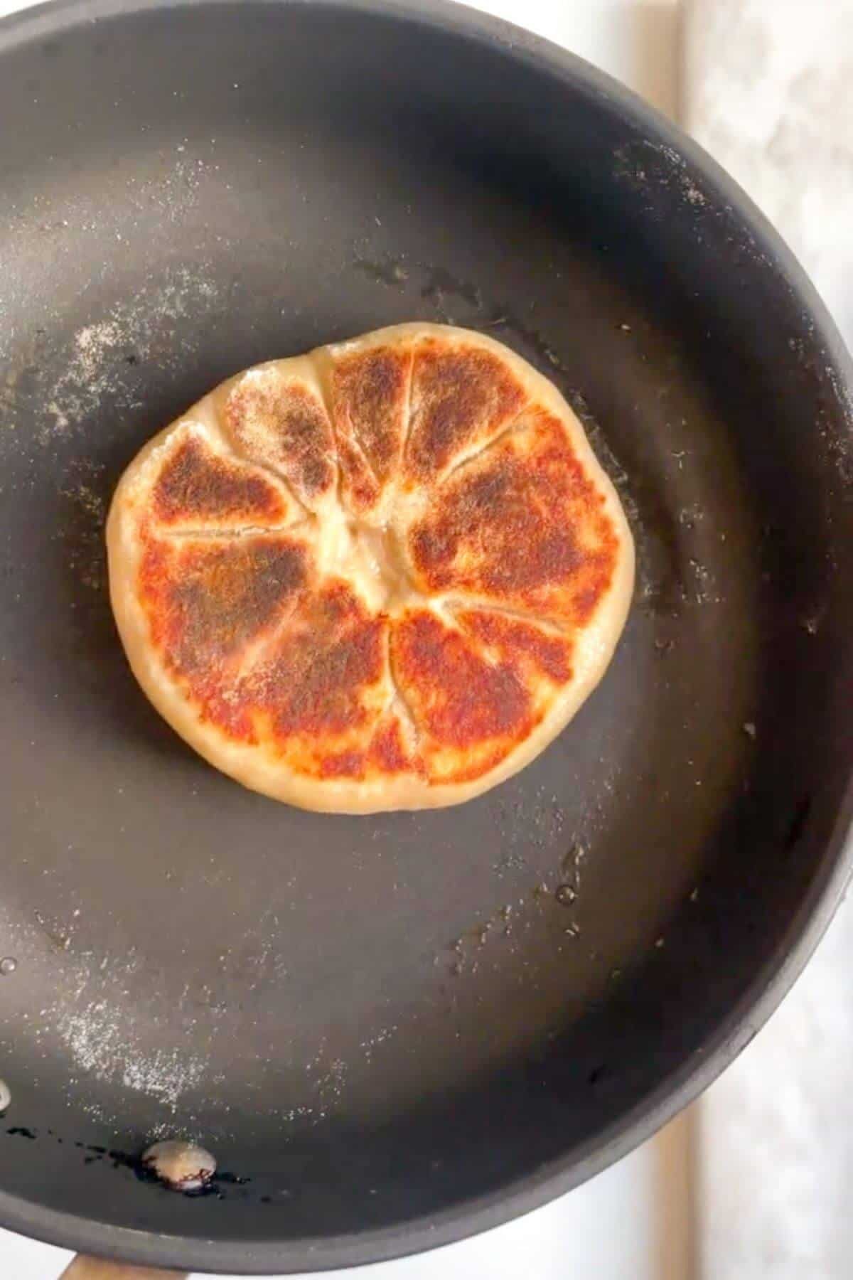 Pan-frying stuffed flatbread in a small pan.