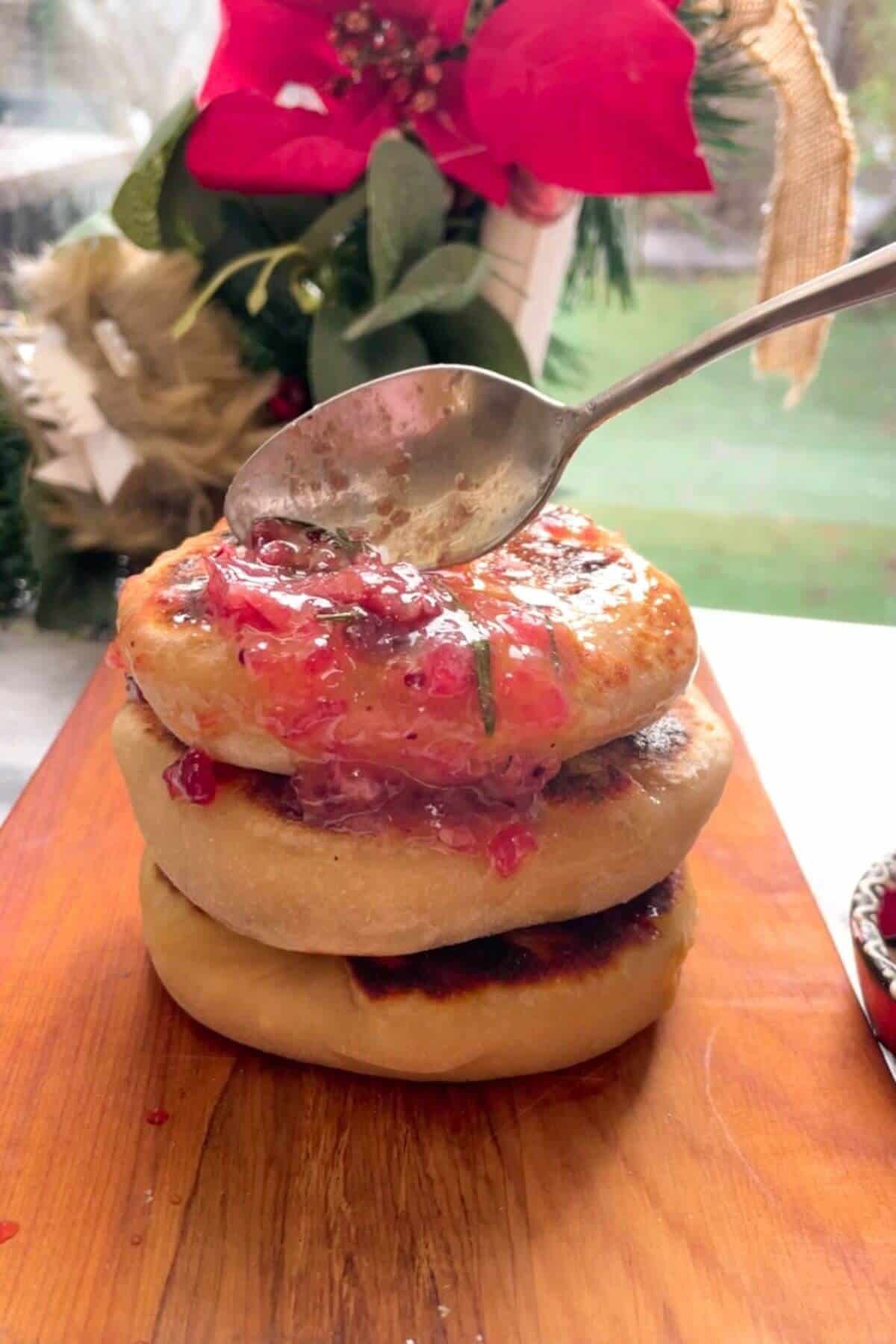Spooning cranberry garlic butter onto pile of stuffed flatbreads.