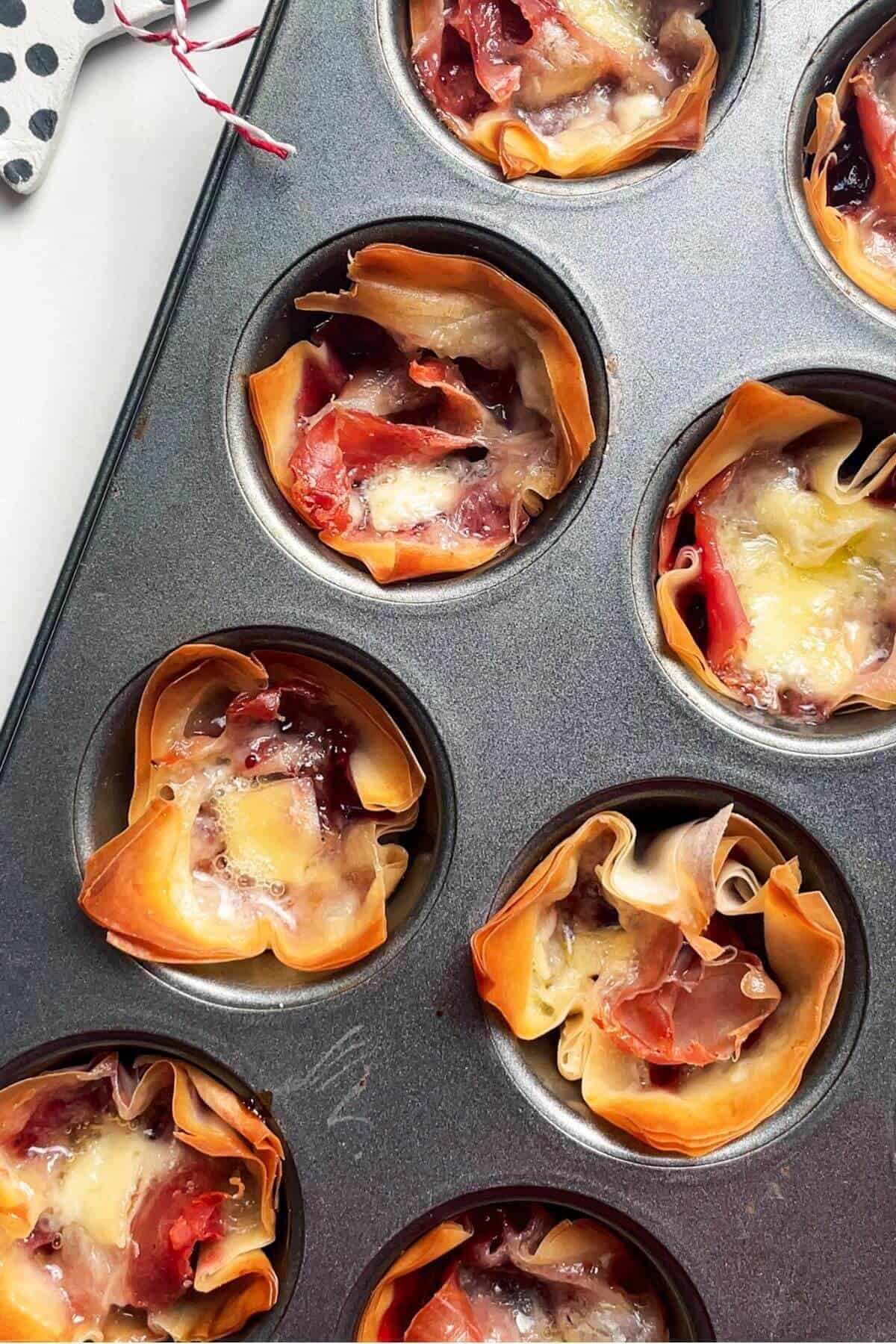 Baked brie filo bites in a mini muffin tin.
