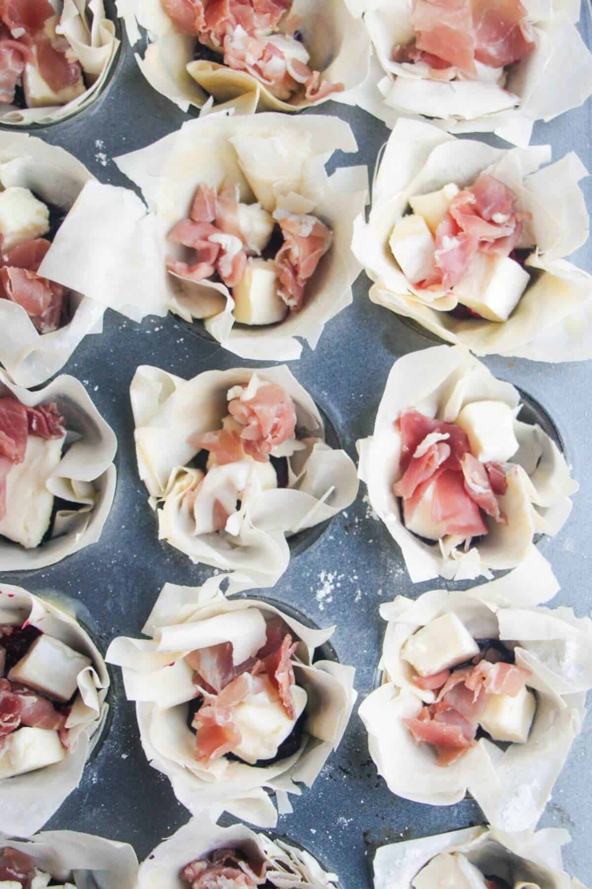 Brie, prosciutto and cranberry sauce in filo pastry cups.