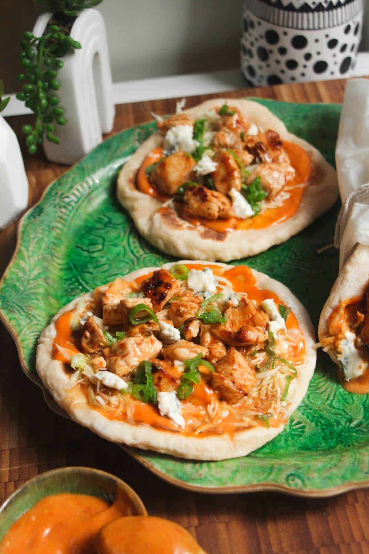Three Buffalo chicken wraps on a large green platter.
