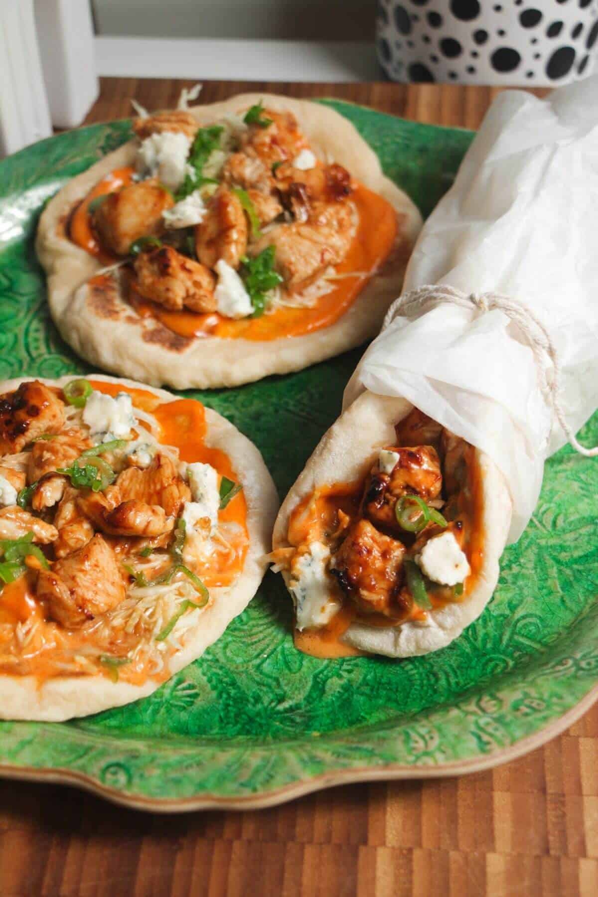 Three Buffalo chicken wraps on a large green platter.