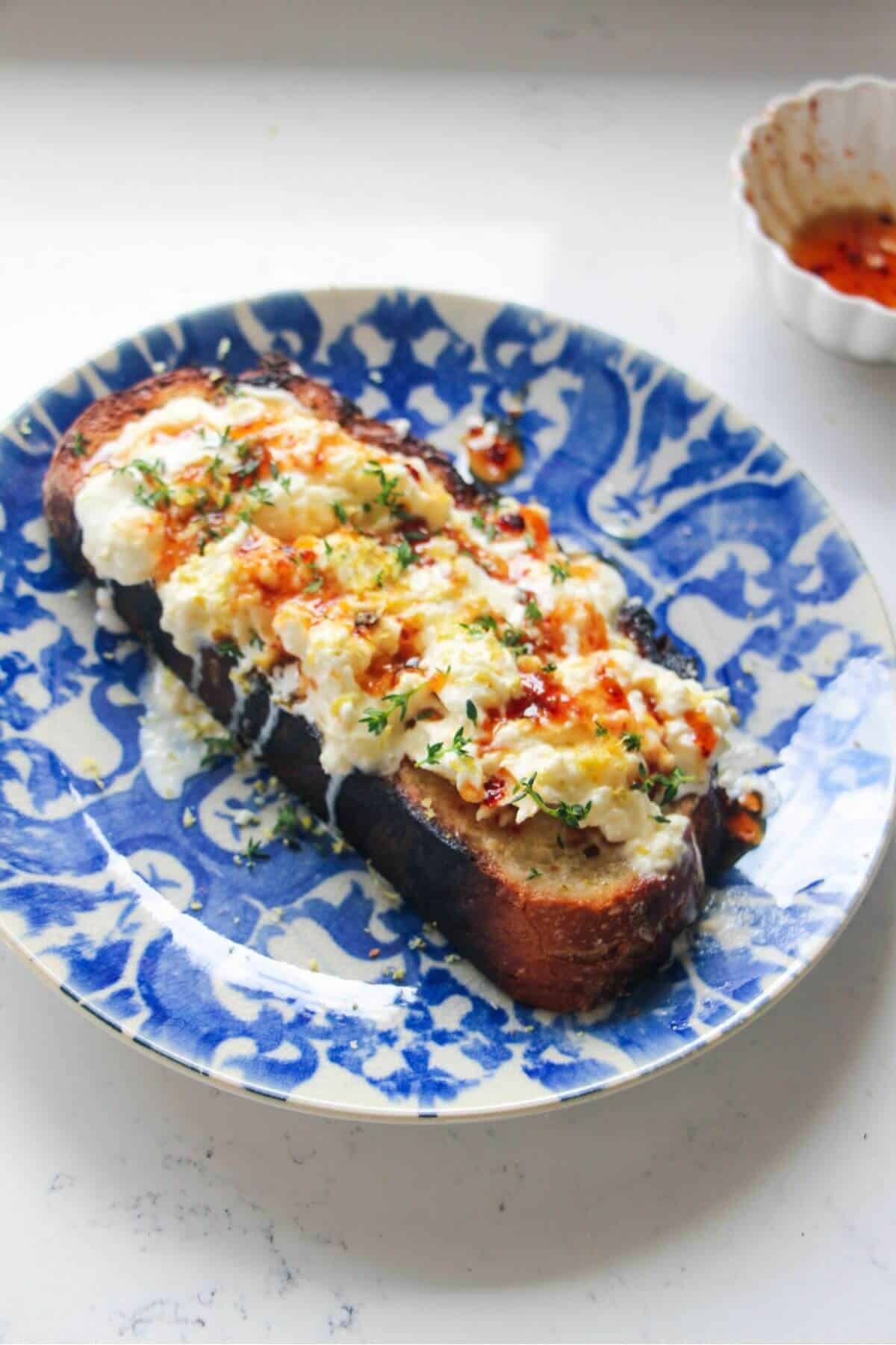 Burrata on a piece of toasted sourdough with hot honey and thyme on top.