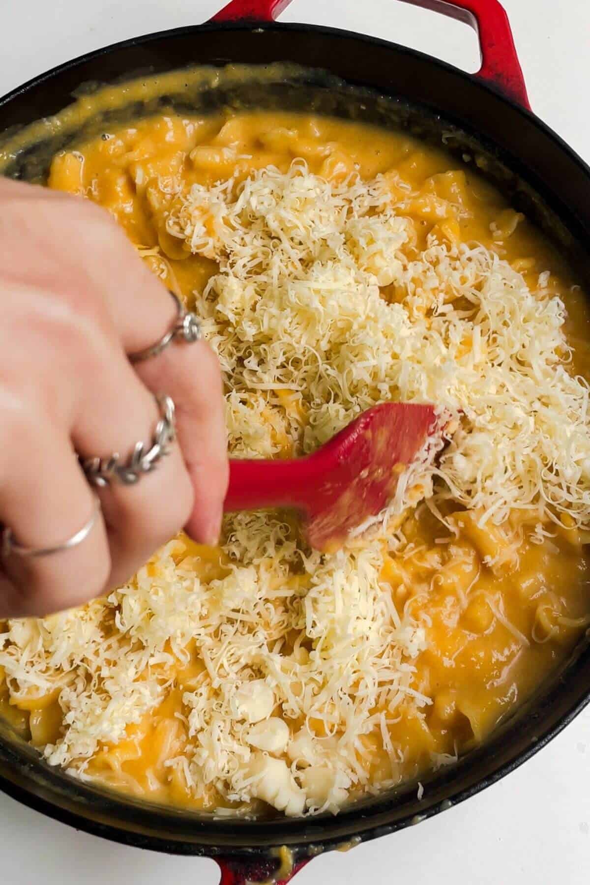 Grated cheese being stirred into butternut squash mac and cheese.
