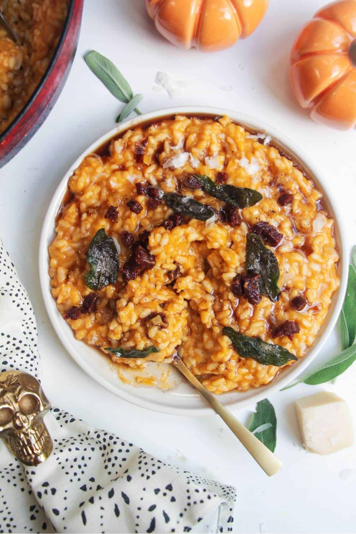 Butternut squash risotto on a small white plate, topped with sage brown butter and chorizo.