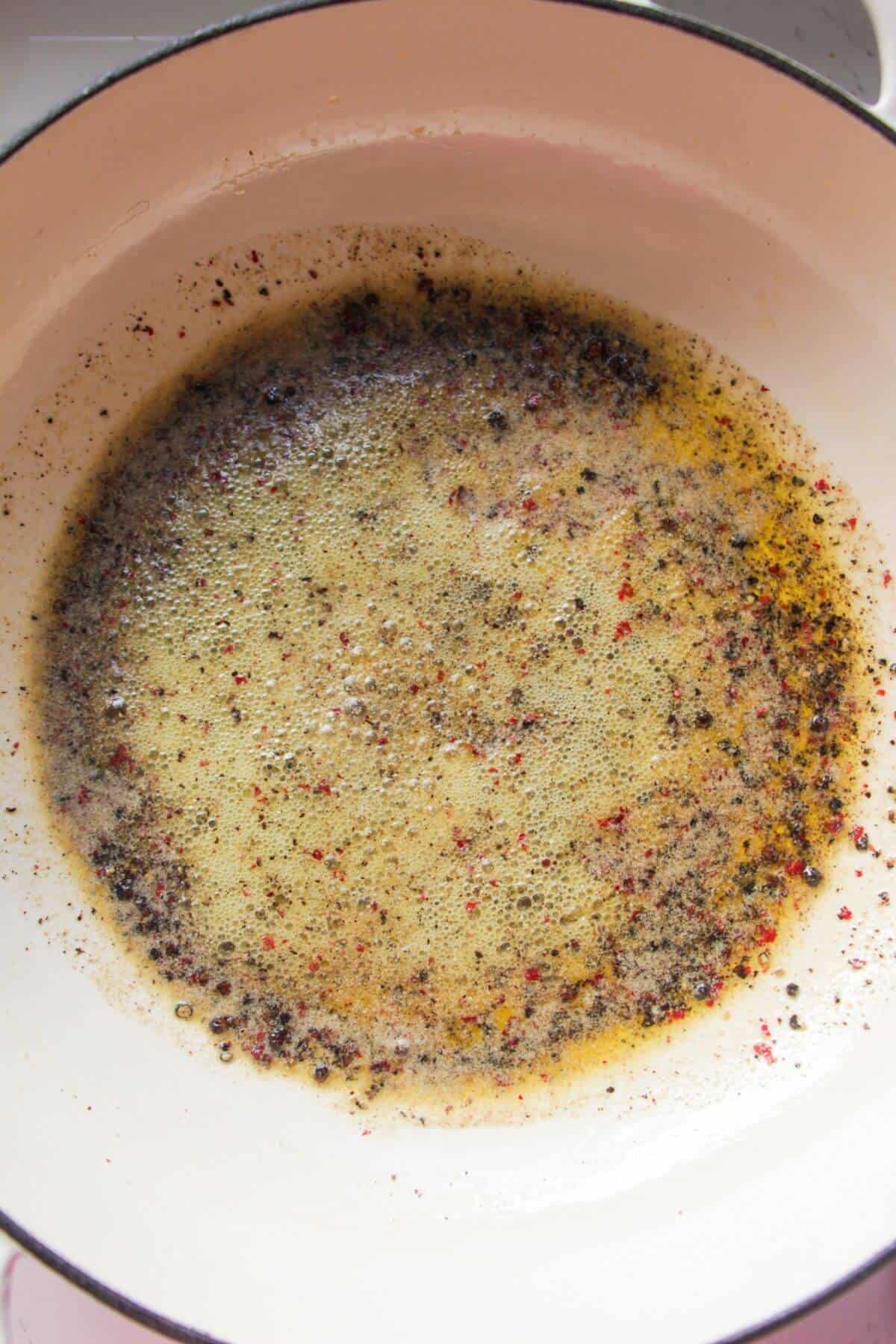 Bubbling melted butter and black pepper in a pan.